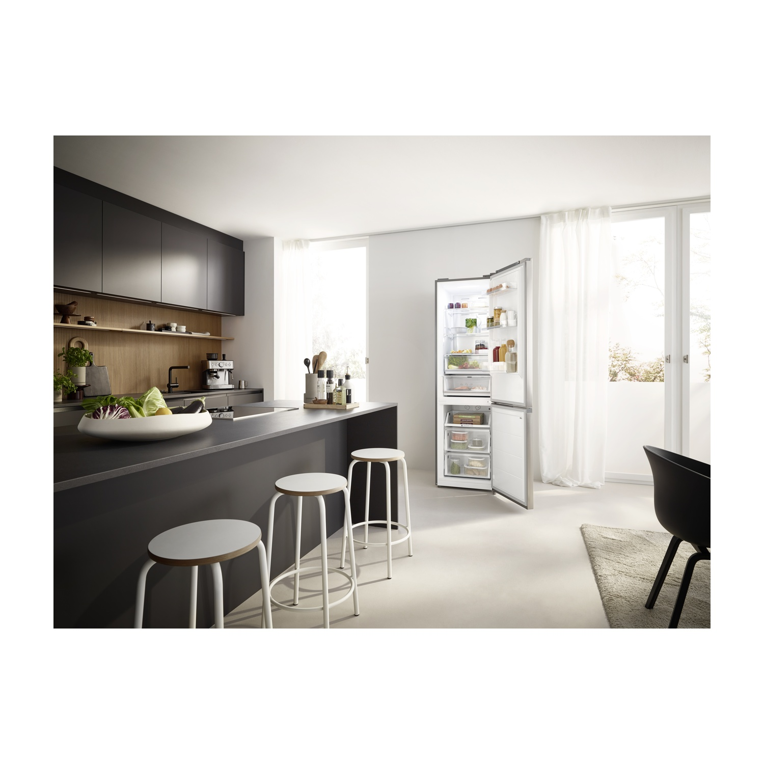 Cucina moderna con frigo aperto, sgabelli e verdure sul bancone. La luce naturale inonda la stanza.