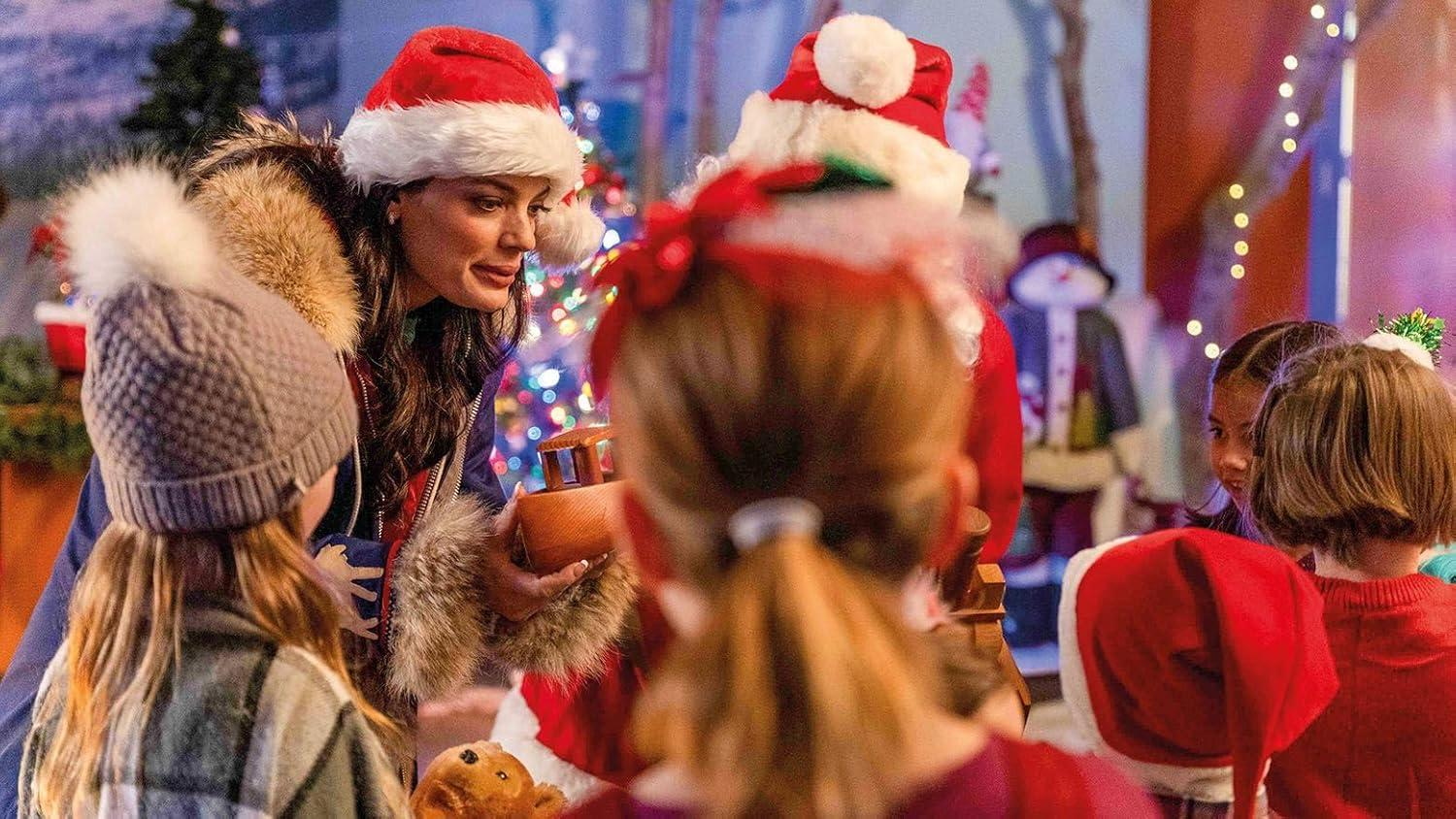 Menschen, darunter eine Frau mit Weihnachtsmütze, Kinder und der Weihnachtsmann, versammeln sich in der Nähe eines Weihnachtsbaums.