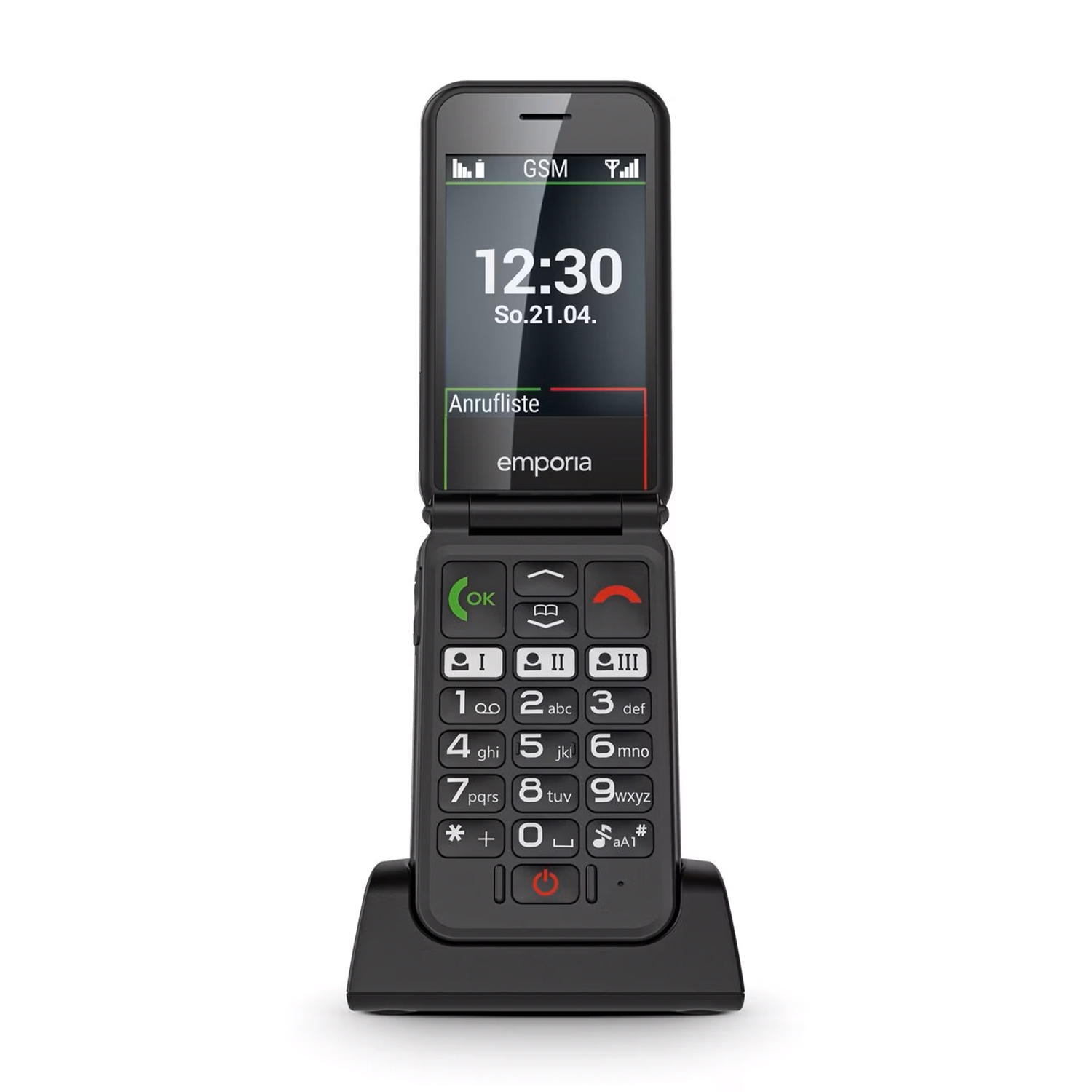 Un telefono a conchiglia nero è aperto, mostrando l'ora. È in una base di ricarica. Lo schermo mostra l'ora e la parola 'Anrufliste'.