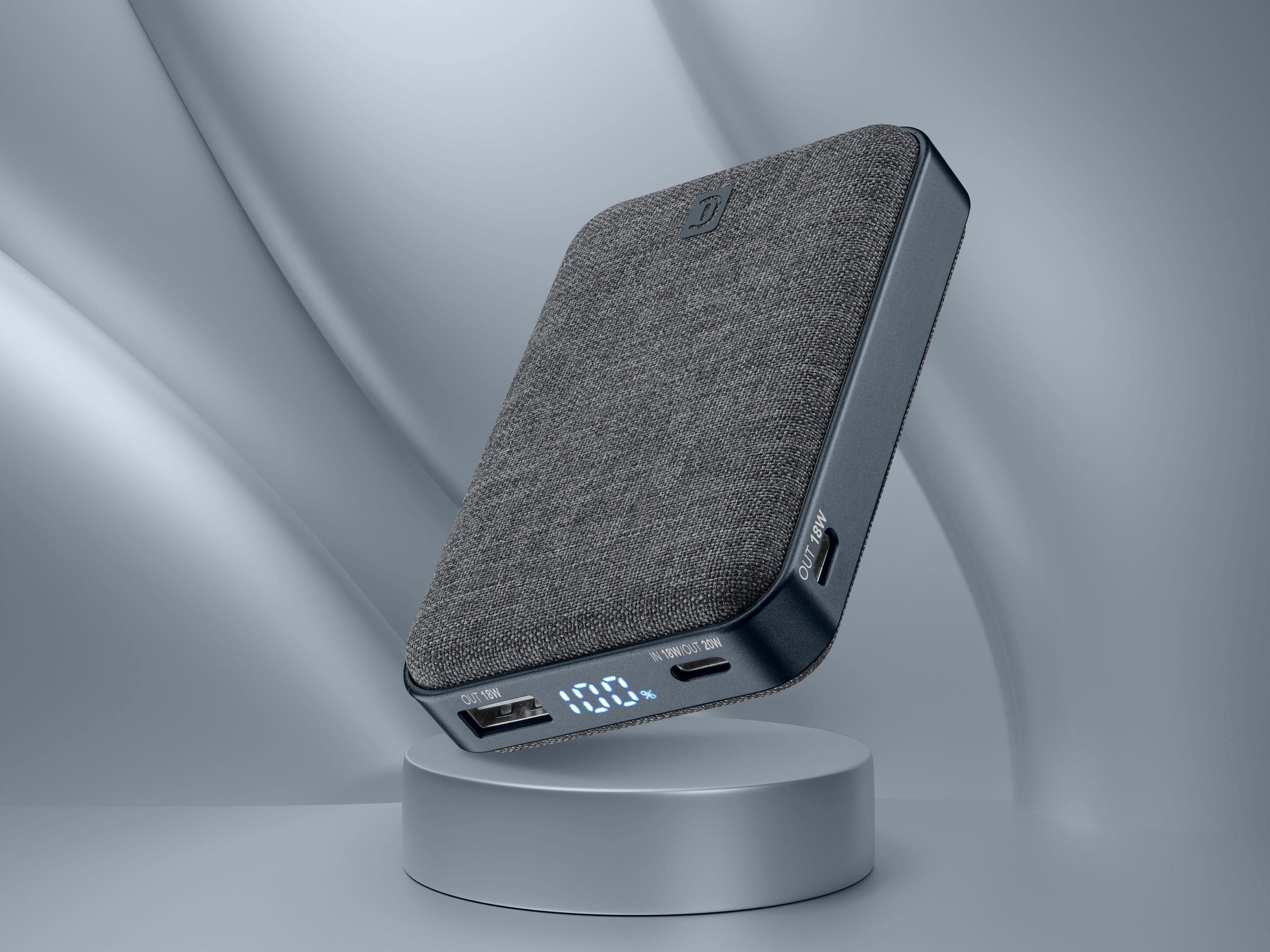 Eine graue Powerbank steht auf einem Podest. Sie zeigt 100 % Ladung an. Ein grauer Hintergrund befindet sich dahinter.