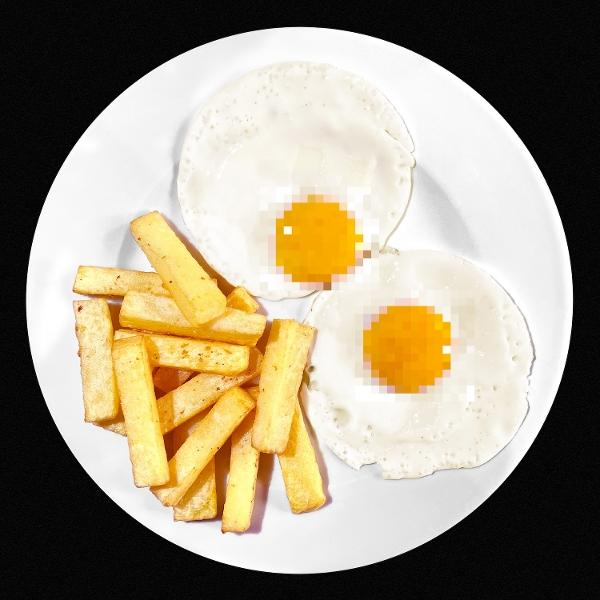 Zwei Spiegeleier mit flüssigem Eigelb neben einem Haufen Pommes frites auf einem weißen Teller.
