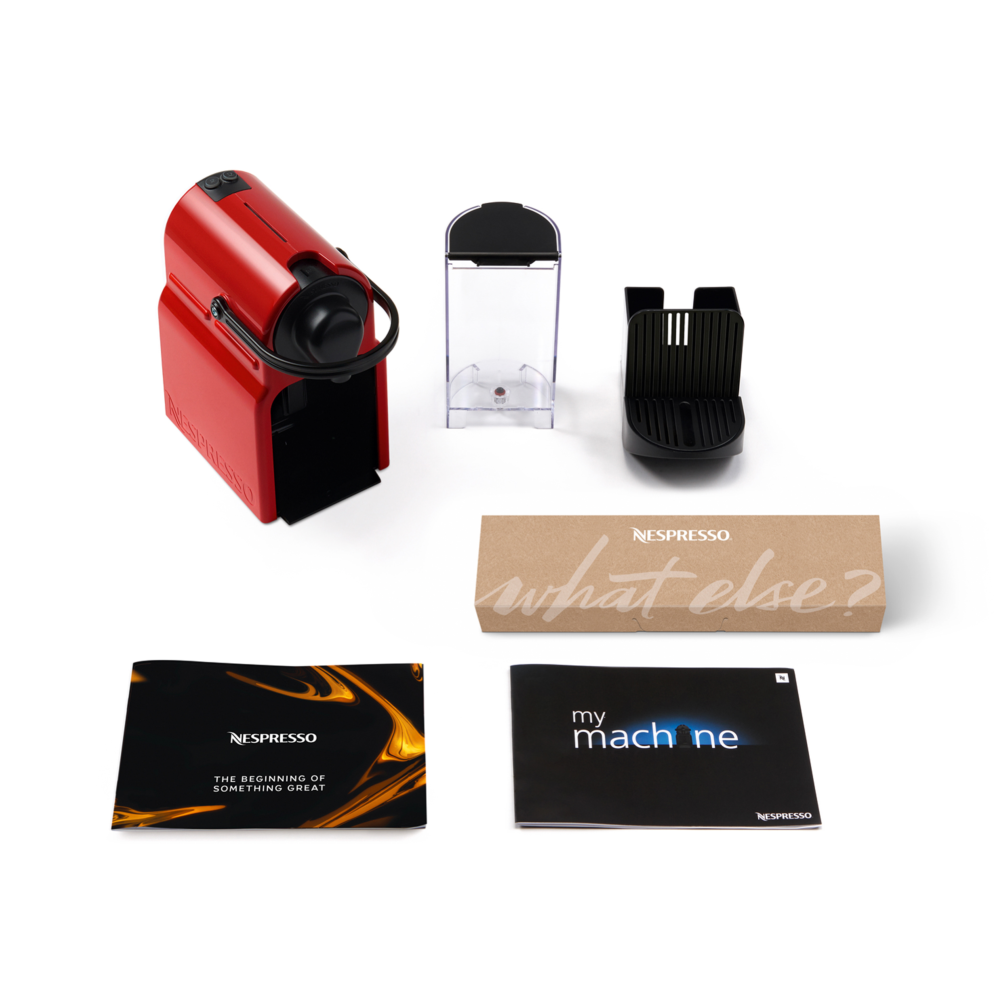 Una máquina Nespresso roja con accesorios, incluyendo un depósito de agua, soporte para cápsulas y folletos, sobre una superficie blanca.