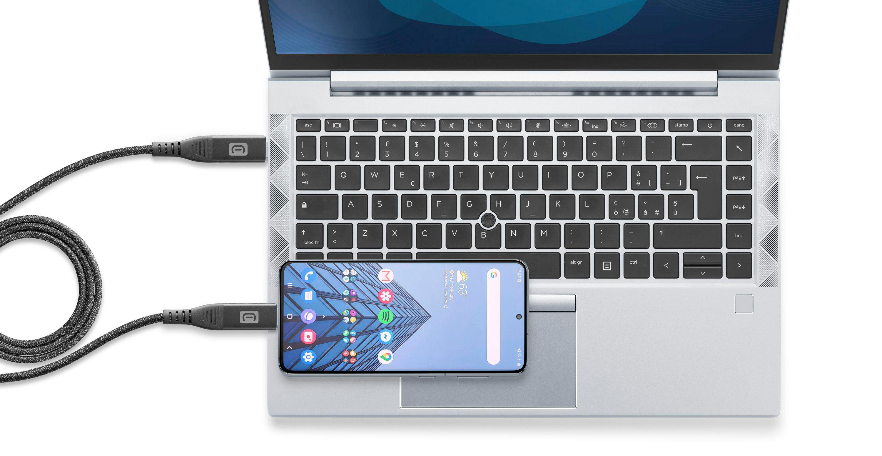 Laptop mit per Kabel verbundenem Telefon. Telefon zeigt Wetter und Uhrzeit an. Kabel ist grau.