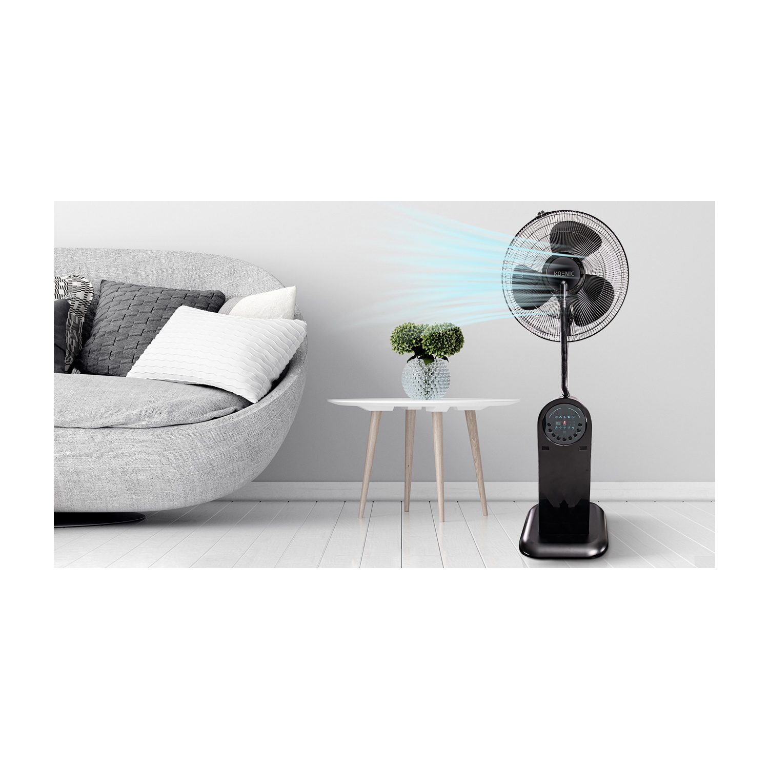 Un ventilatore a piantana nero in una stanza. Sono presenti anche un divano grigio, un tavolino bianco con una pianta. Pavimento e parete bianchi.