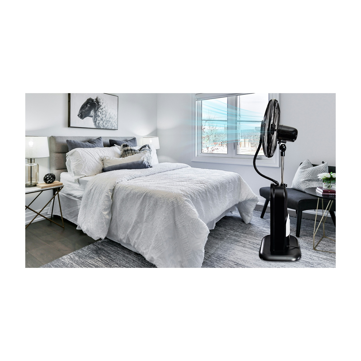 Una camera da letto con un letto, un ventilatore, una finestra e una sedia. Il ventilatore è nero e soffia aria. Un quadro di pecora è appeso al muro.