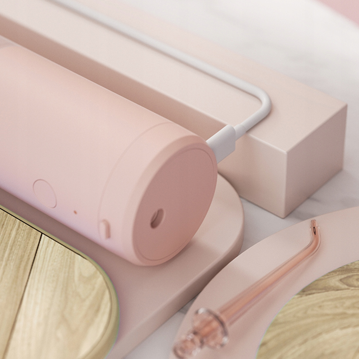 Różowy irygator do jamy ustnej z białym kablem ładującym, umieszczony na różowych geometrycznych kształtach. Dodatkowa przezroczysta dysza.