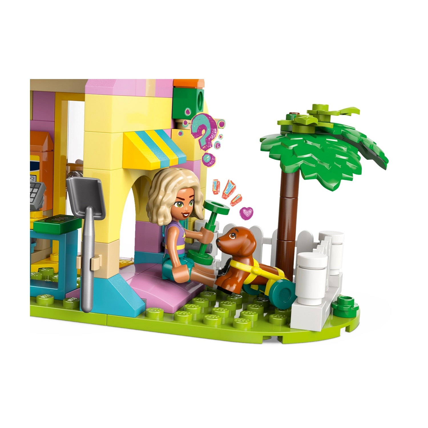 Set Lego con una ragazza, un cane, una palma e un edificio. La ragazza tiene un oggetto verde. Il cane indossa un'imbracatura gialla.