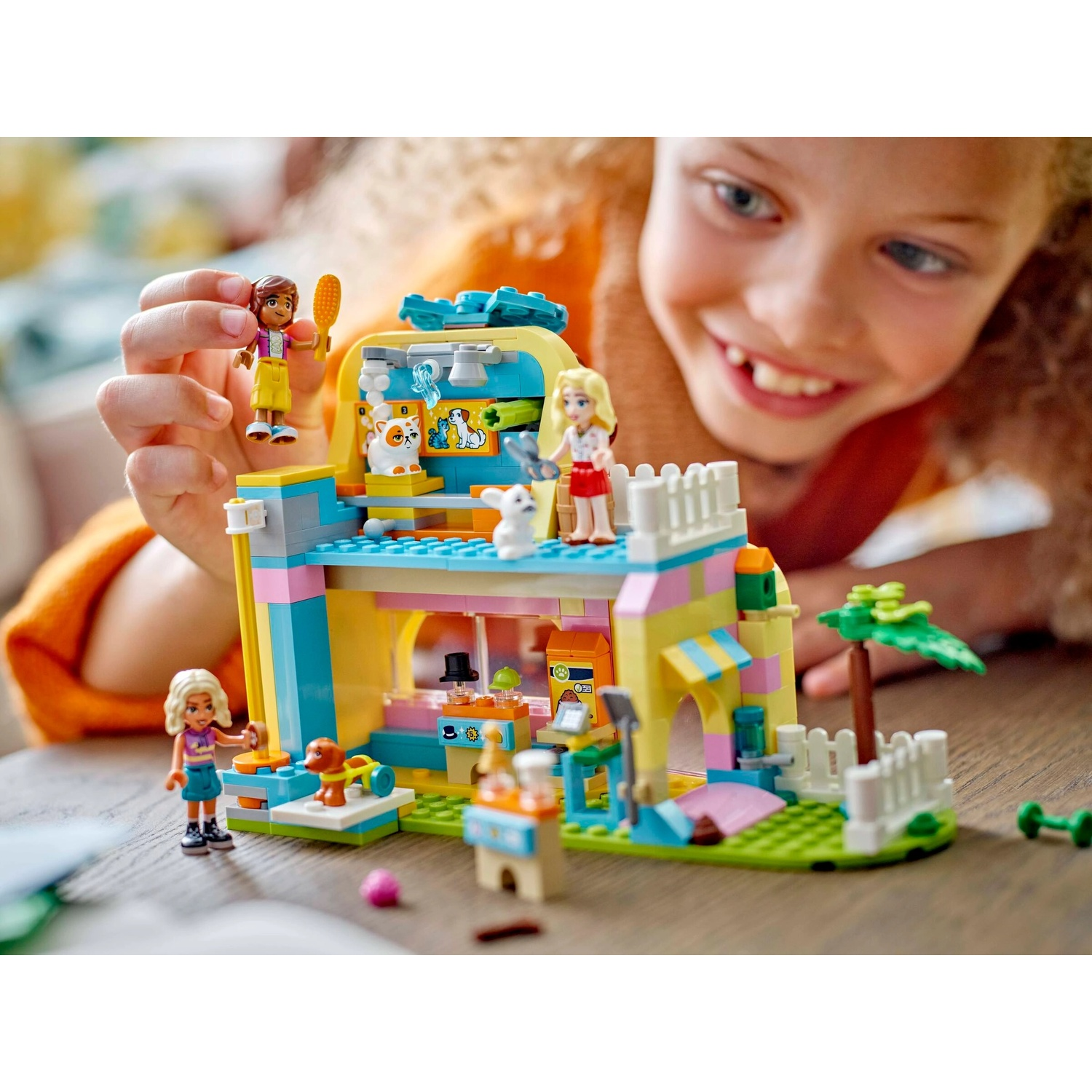Un bambino gioca con un set Lego. Il set raffigura un negozio di animali colorato con figurine e animali in miniatura.