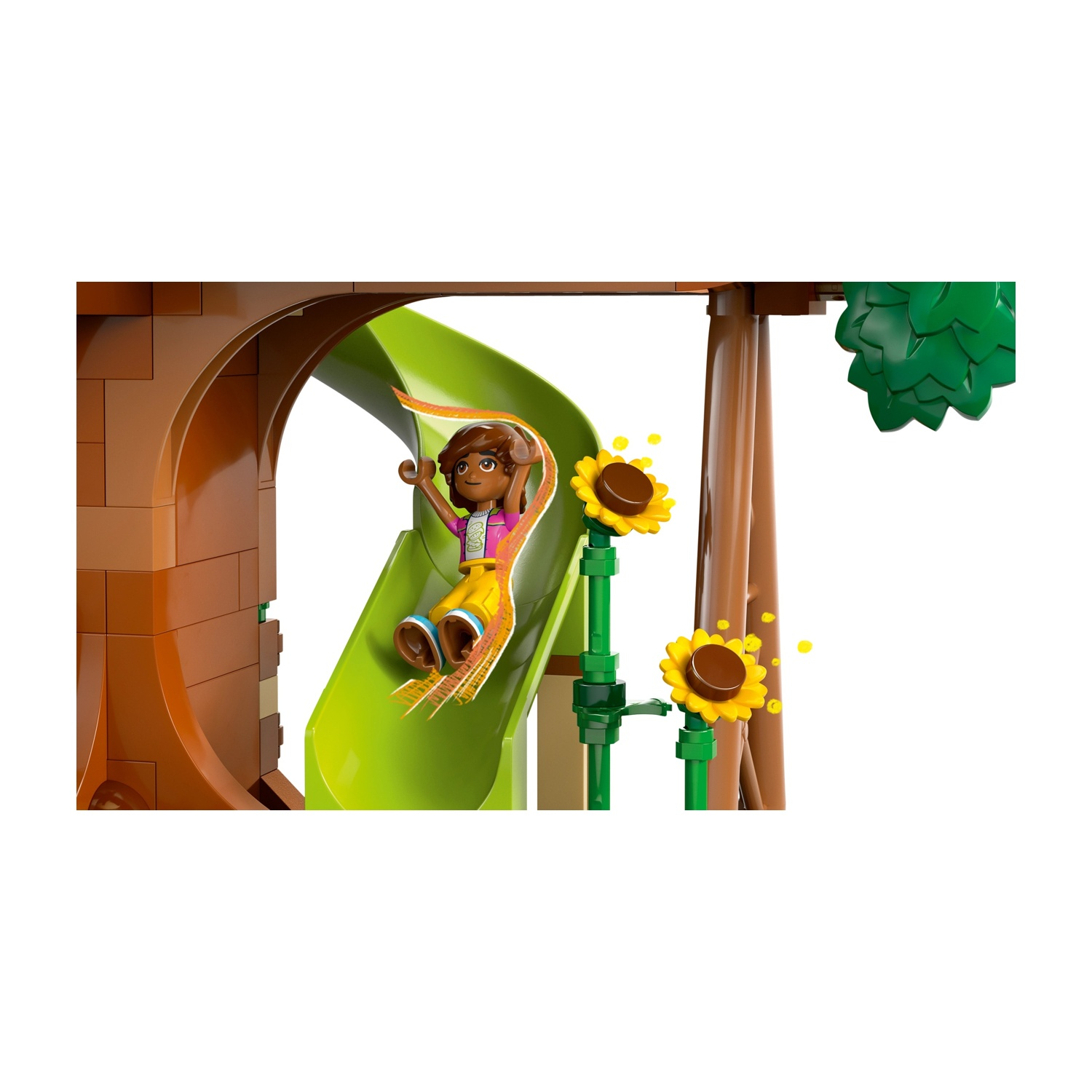 Un personaggio Lego scivola giù da uno scivolo verde. Tronco d'albero marrone e girasoli ai lati. Lo sfondo è bianco.