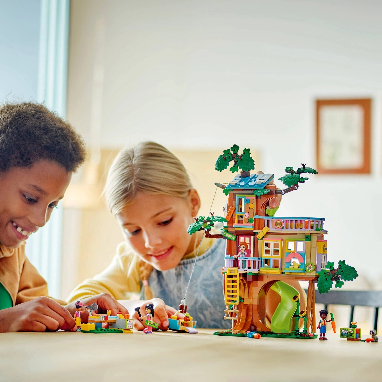 Due bambini costruiscono una colorata casa sull'albero con figure Lego. La casa sull'albero ha uno scivolo, una scala e balconi. Ci sono figurine.
