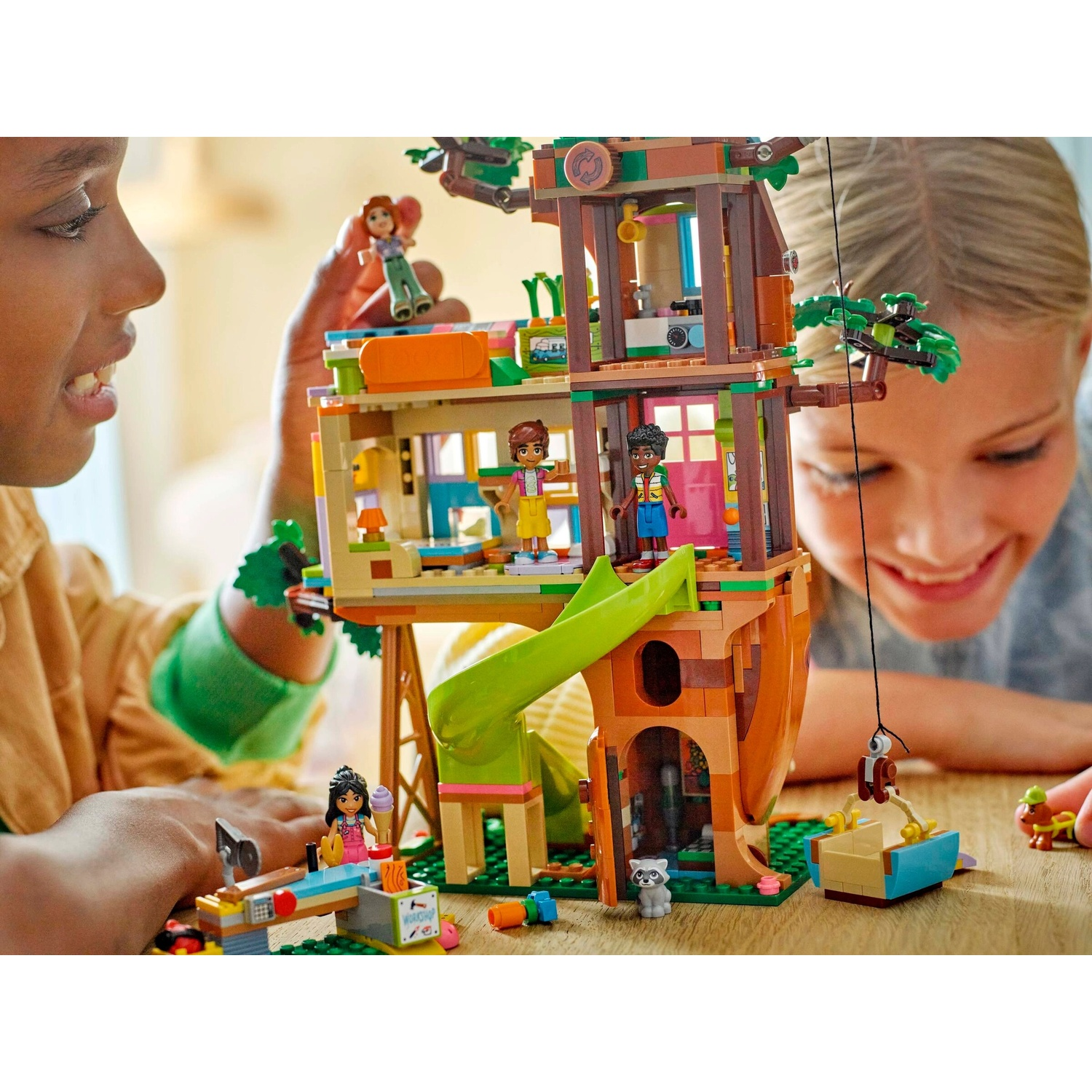 Una casa sull'albero Lego con personaggi. I bambini ci giocano. La casa sull'albero ha uno scivolo, un'altalena e varie stanze.