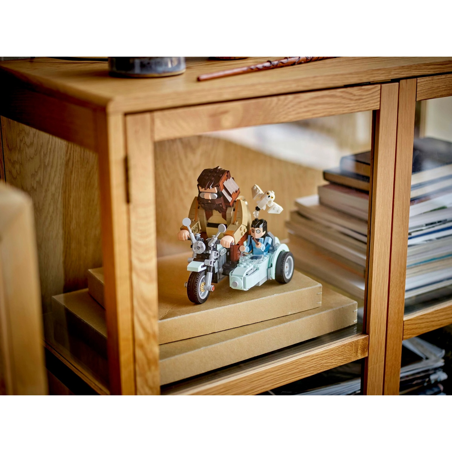 Moto LEGO con sidecar. Hagrid guida, Harry nel sidecar con gufo. Su cartone, dentro un armadio di legno.