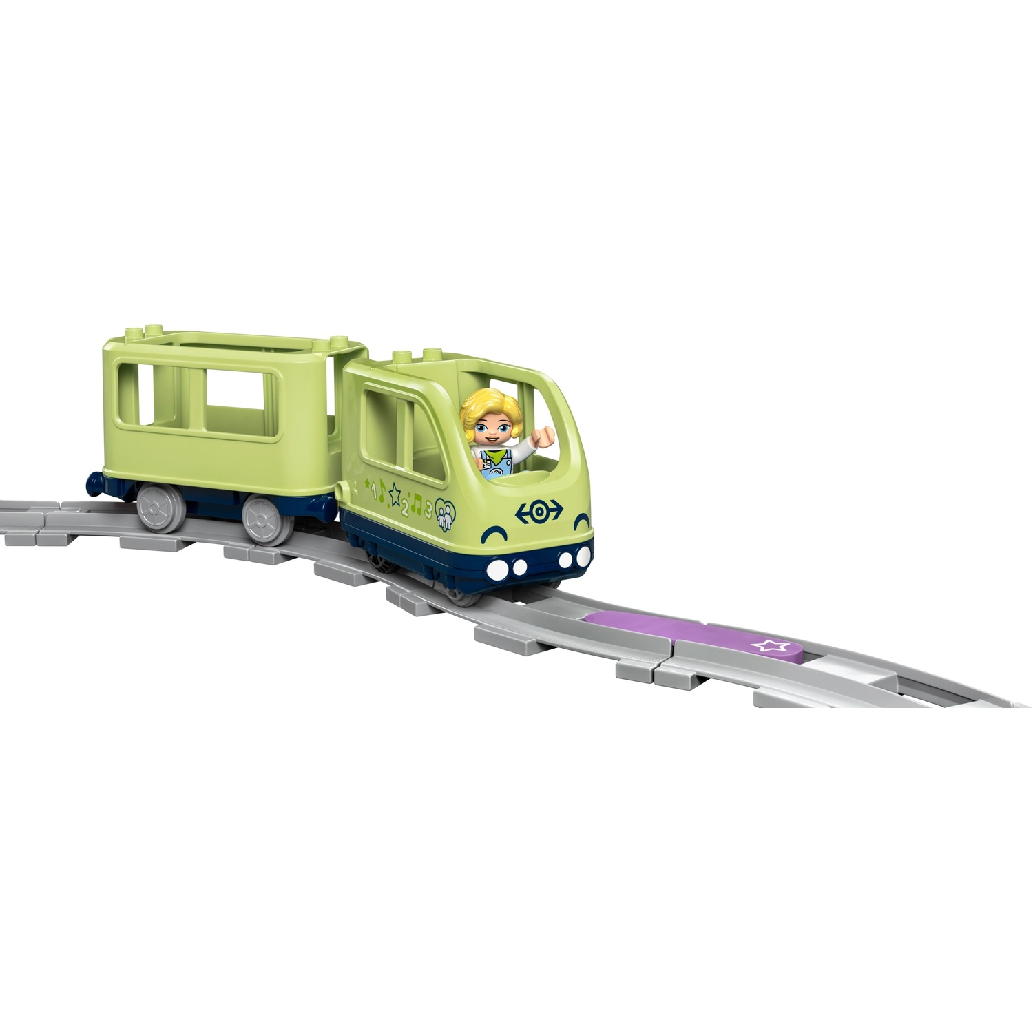 Un trenino giocattolo verde con una figura bionda è su un binario. Il treno è su sfondo bianco con una stella viola sul binario.