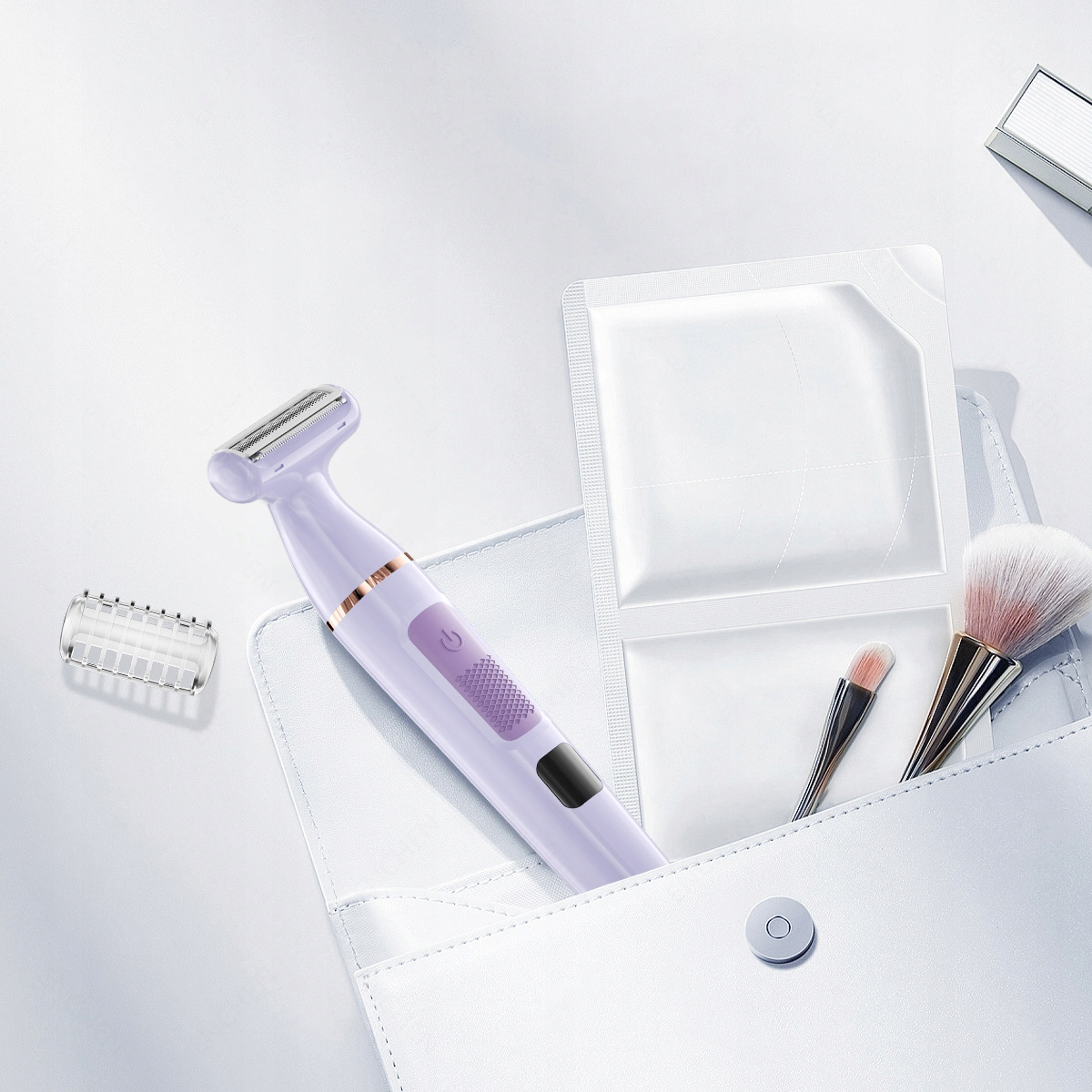 Fioletowa golarka elektryczna, pędzle do makijażu i białe opakowania są w białej torebce, na białej powierzchni.