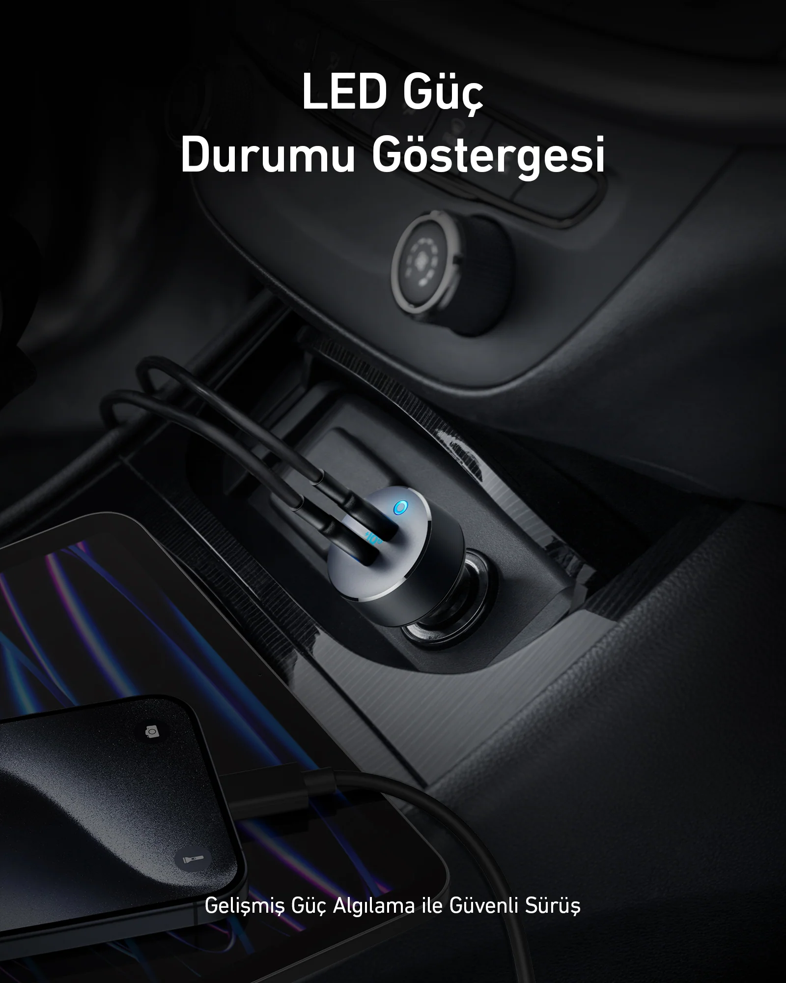 Araba şarj cihazı, kabloları arabanın prizine takılı. Bir tablet ve telefon şarj oluyor. Siyah ve gümüş renk şeması.