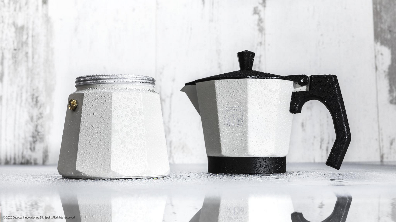 Dos cafeteras moka blancas con detalles negros. Una está desmontada. Ambas están mojadas. El fondo es una superficie de madera blanca.