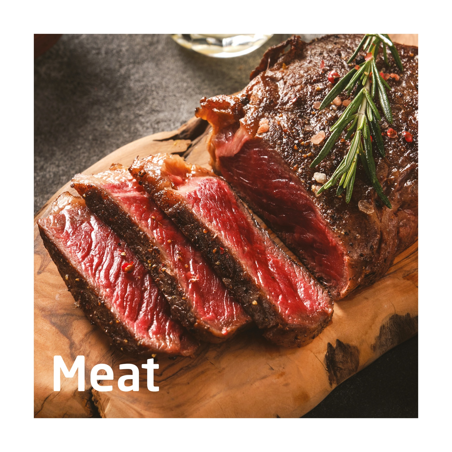 Bistecca a fette su tagliere di legno, guarnita con rosmarino e sale. La carne è rossa e succosa, con crosta scura.