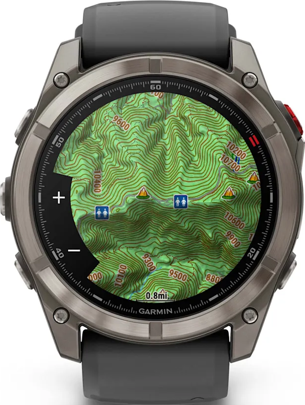 Uno smartwatch argentato mostra una mappa topografica verde con curve di livello, indicatori di altitudine e un logo Garmin.