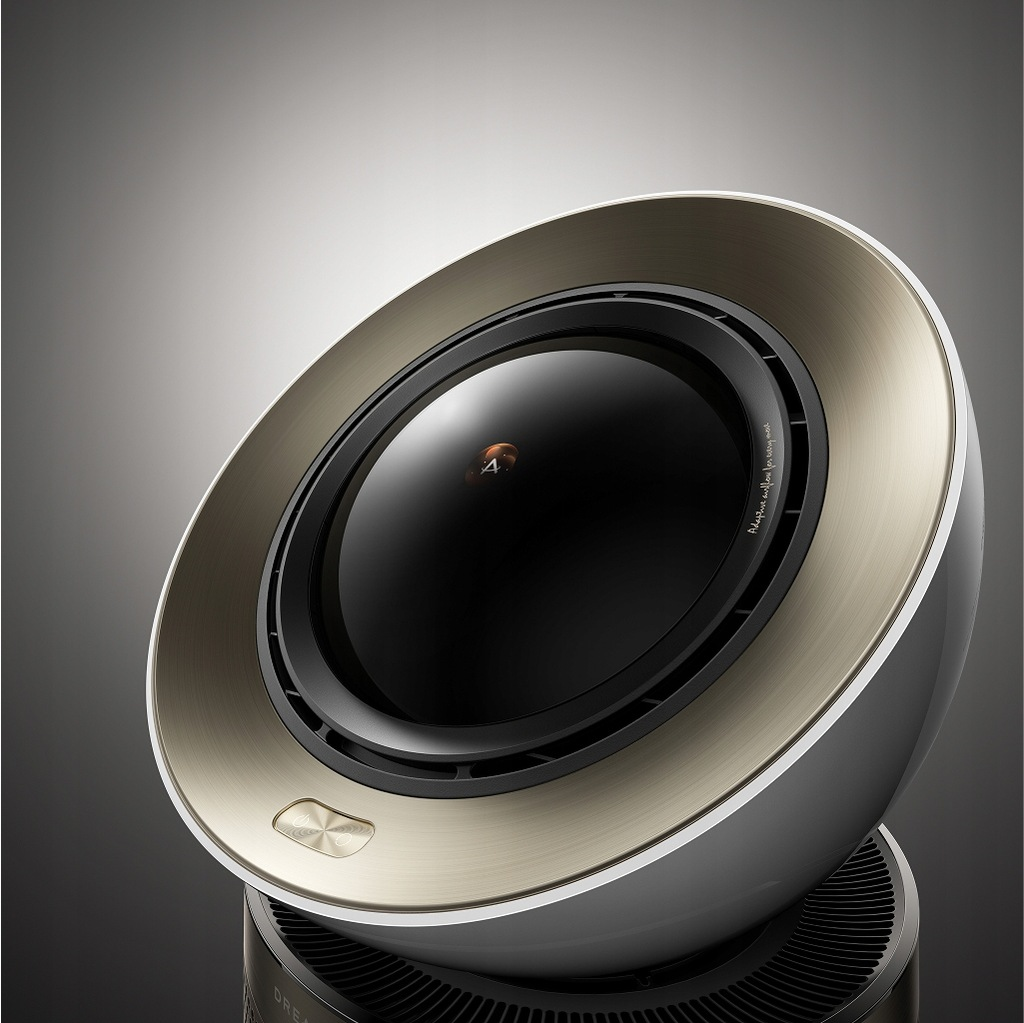 Nowoczesny głośnik ze złotym pierścieniem wokół czarnego środka. Ma biało-szary korpus i stoi na czarnej podstawie.