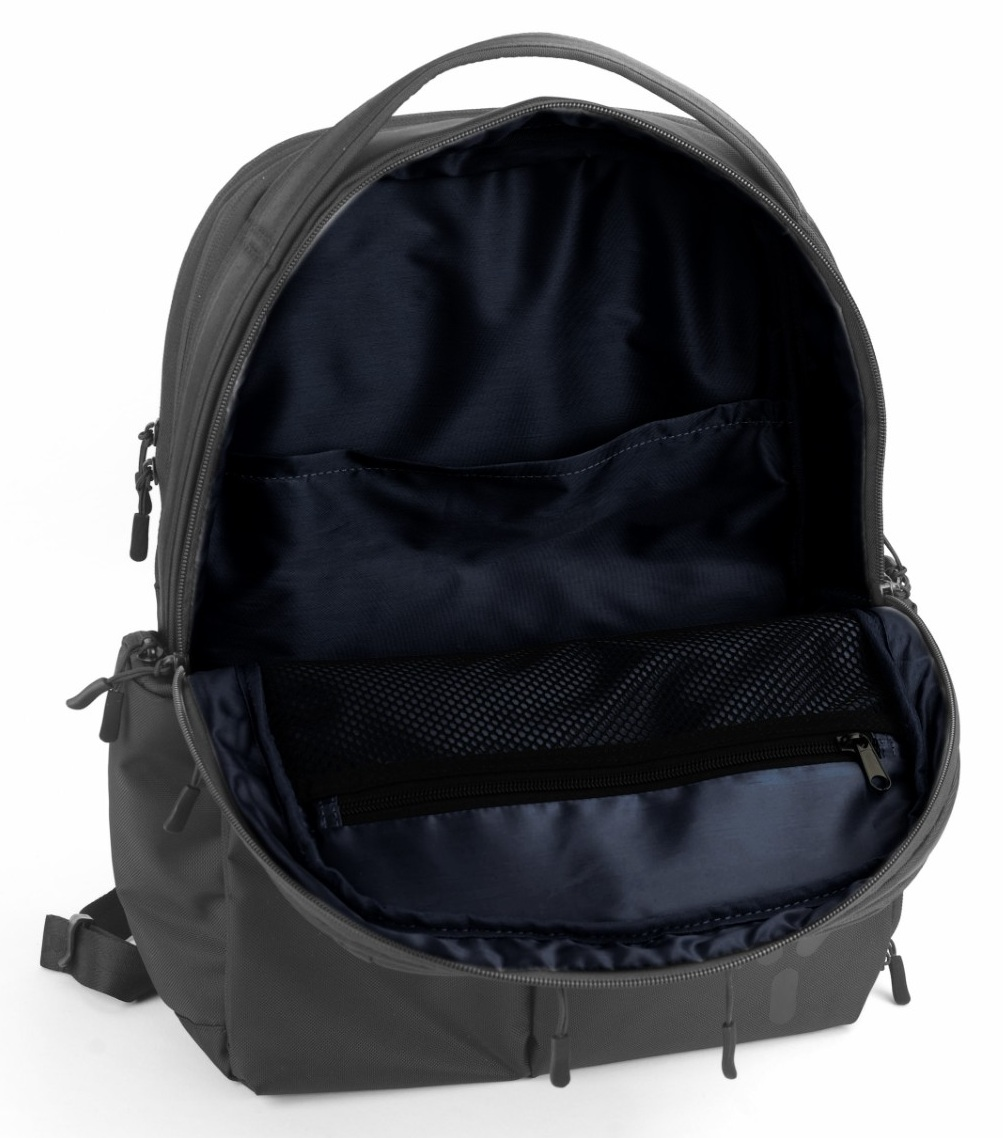 Otwarty czarny plecak z niebieskim wnętrzem. Widoczne zamki błyskawiczne. Uchwyt u góry. Wewnętrzna kieszeń z siatki. Białe tło.