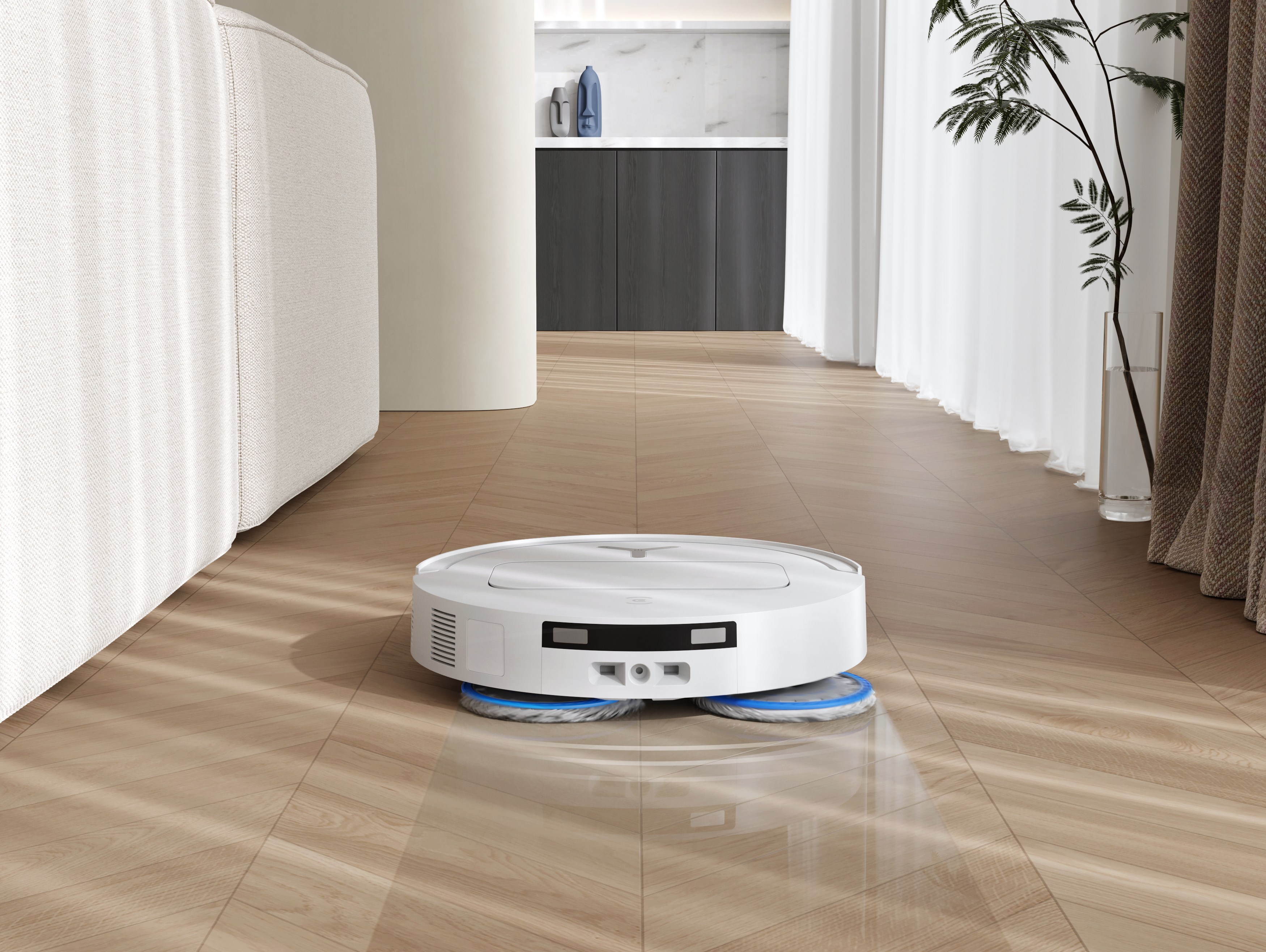 Biały robot sprzątający na drewnianej podłodze. Po lewej sofa. W tle szafka.