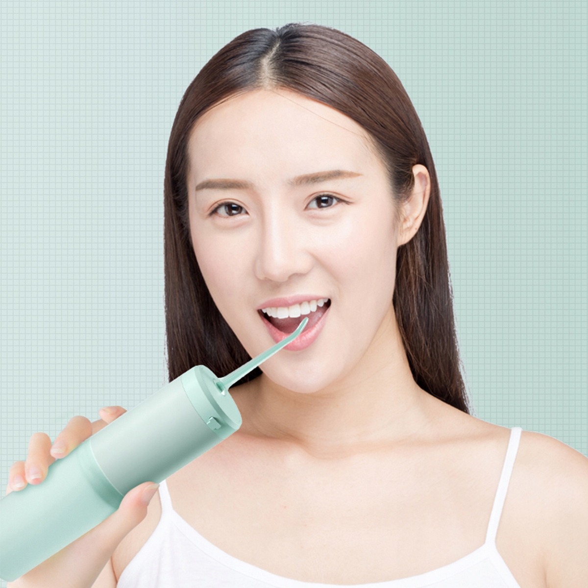 Kobieta uśmiecha się, używając zielonego irygatora. Ma na sobie biały top. Tło jest jasnozielone z siatką.