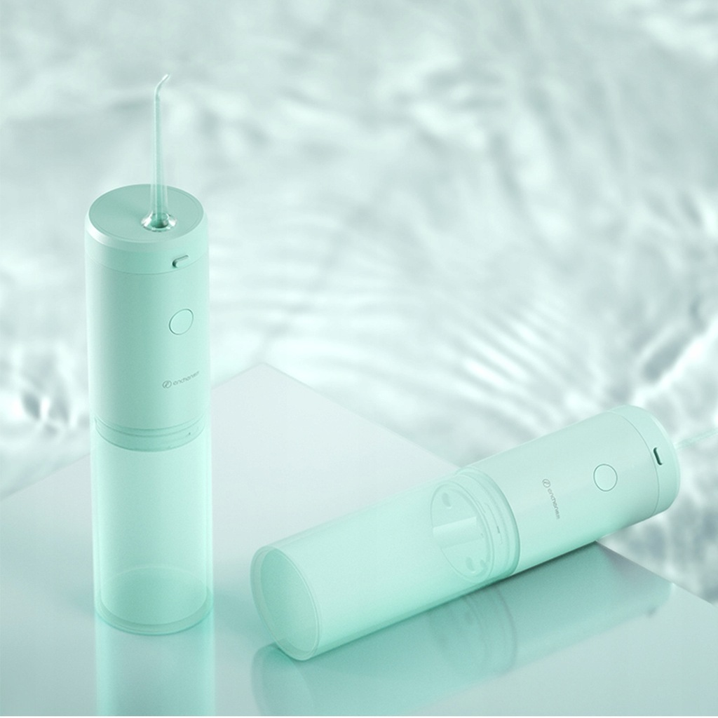 Dwa miętowo-zielone irygatory do zębów. Jeden stoi pionowo, drugi leży. Oba na białej powierzchni, z wodnistym tłem.