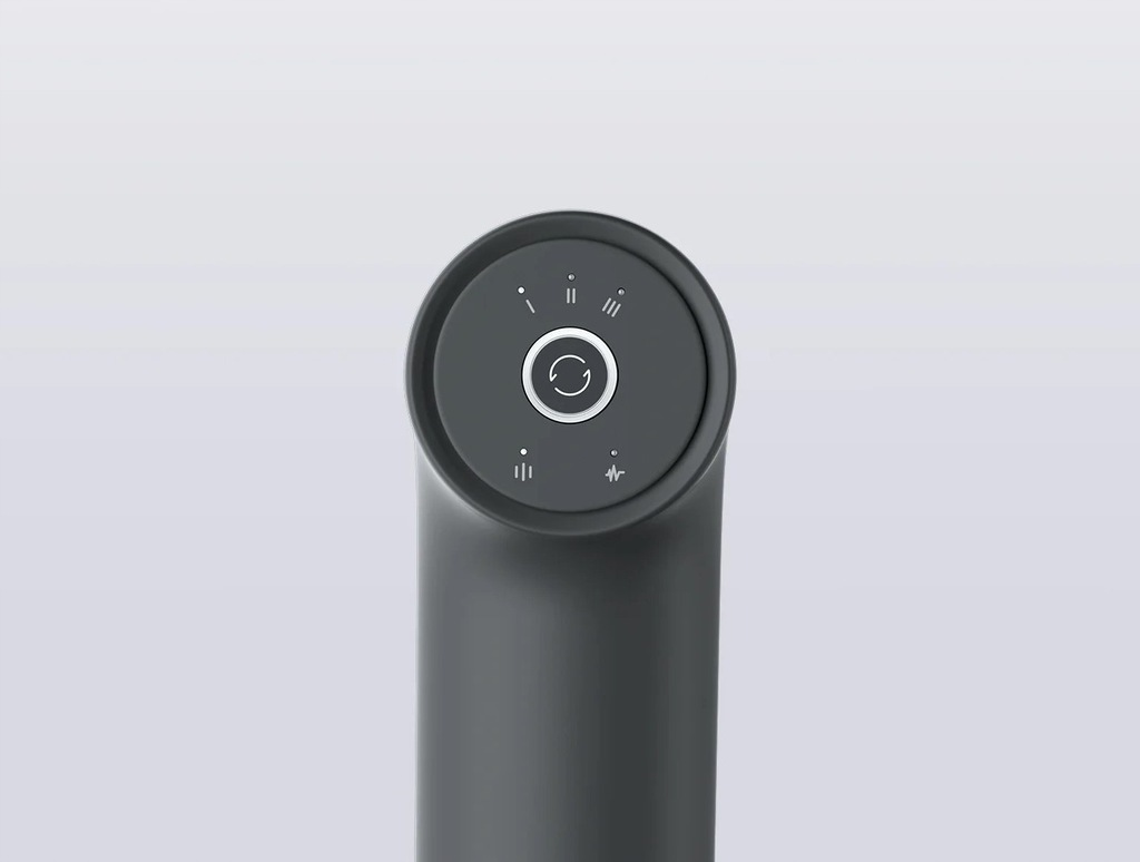 Zbliżenie ciemnoszarego pistoletu do masażu. Ma okrągły panel sterowania z przyciskami i wskaźnikami. Tło jest jasnoszare.