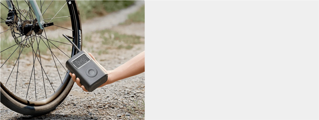 Osoba używa pompki do pompowania opony rowerowej. Koło roweru jest na pierwszym planie, a pompka trzymana jest w dłoni.