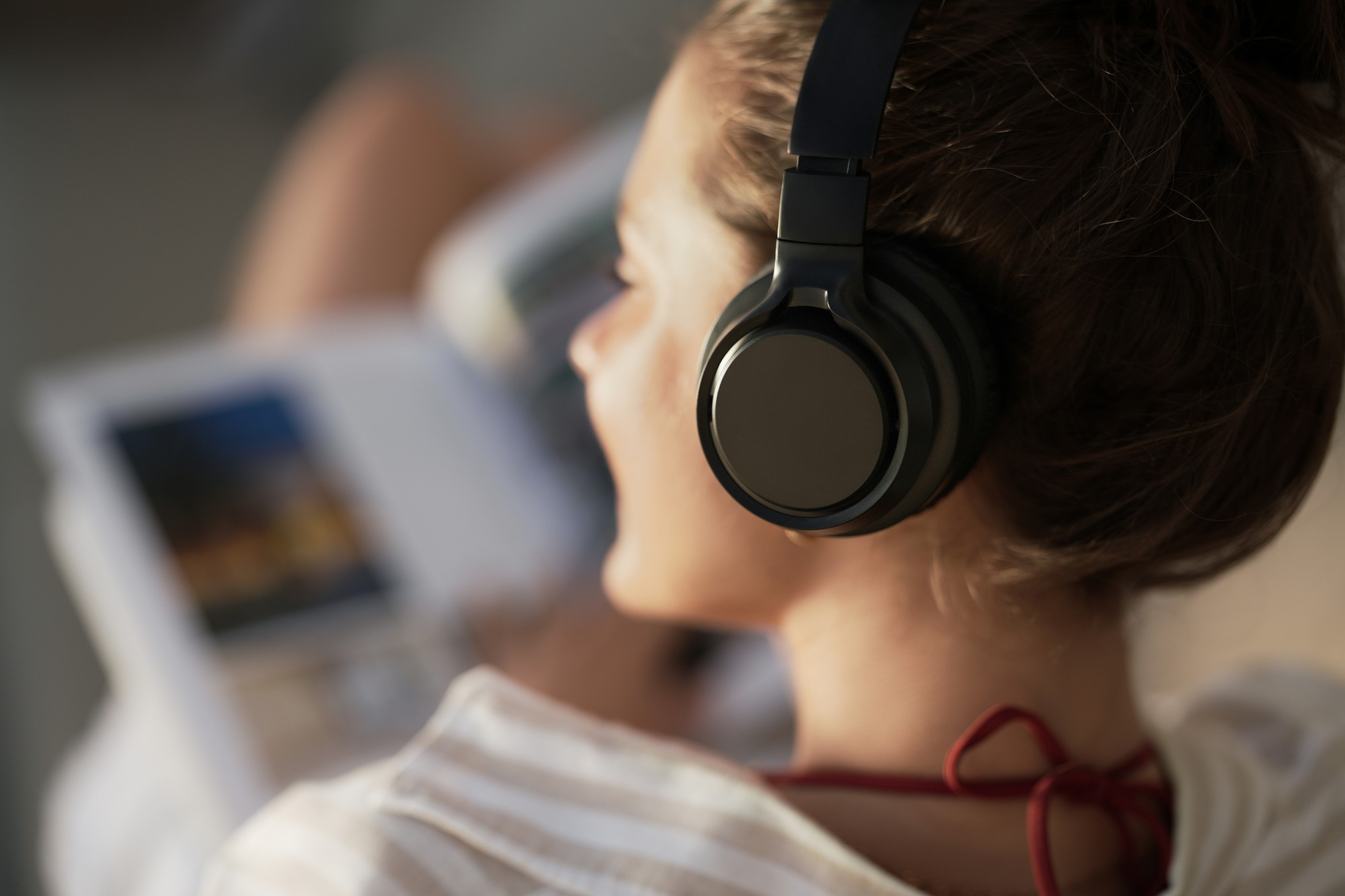 Kobieta nosi czarne słuchawki, patrząc na książkę. Widoczna jest jej biała koszula. Czerwony krawat na szyi.