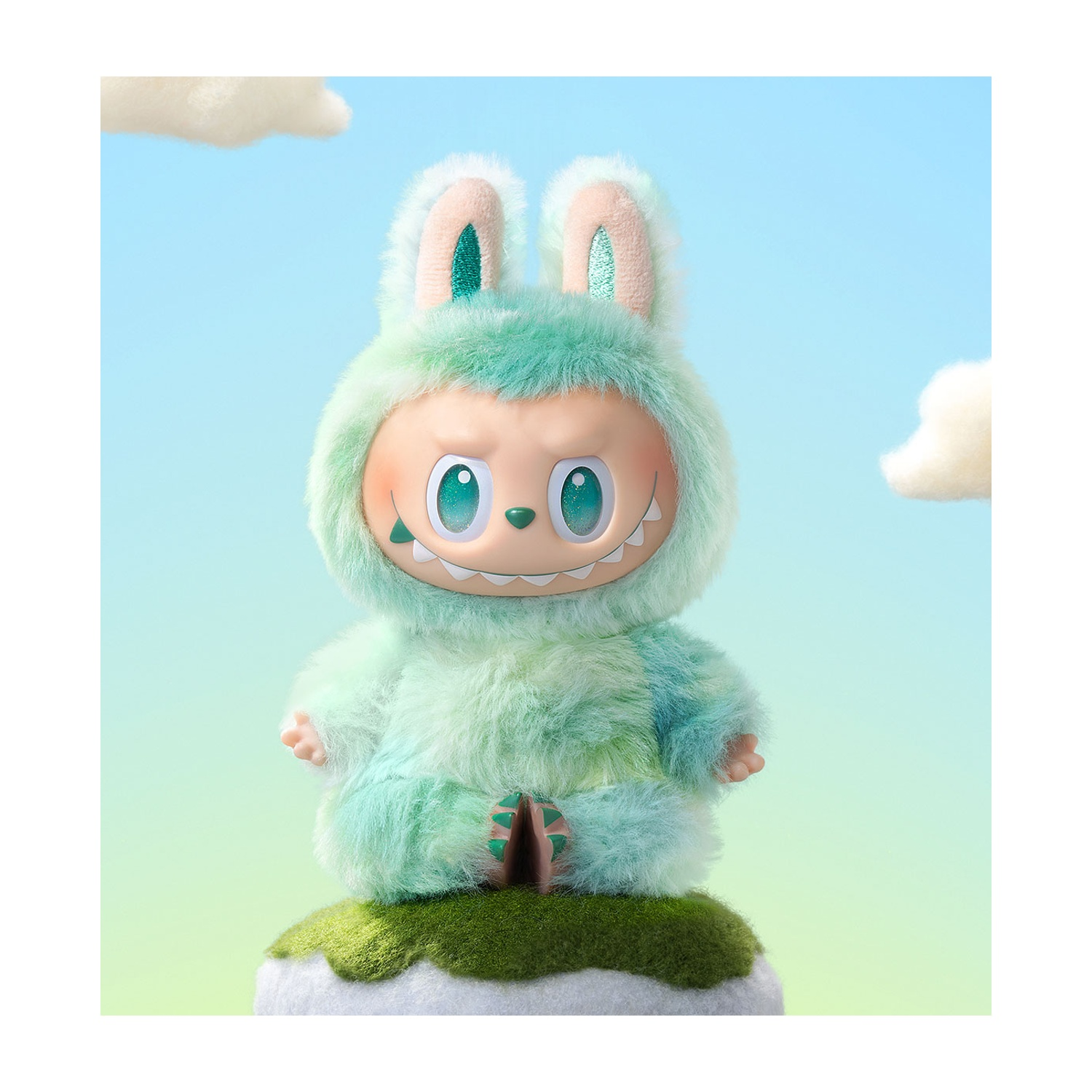 Una figura di peluche con orecchie da coniglio e un sorriso dentuto è su una collina erbosa contro un cielo blu con nuvole.