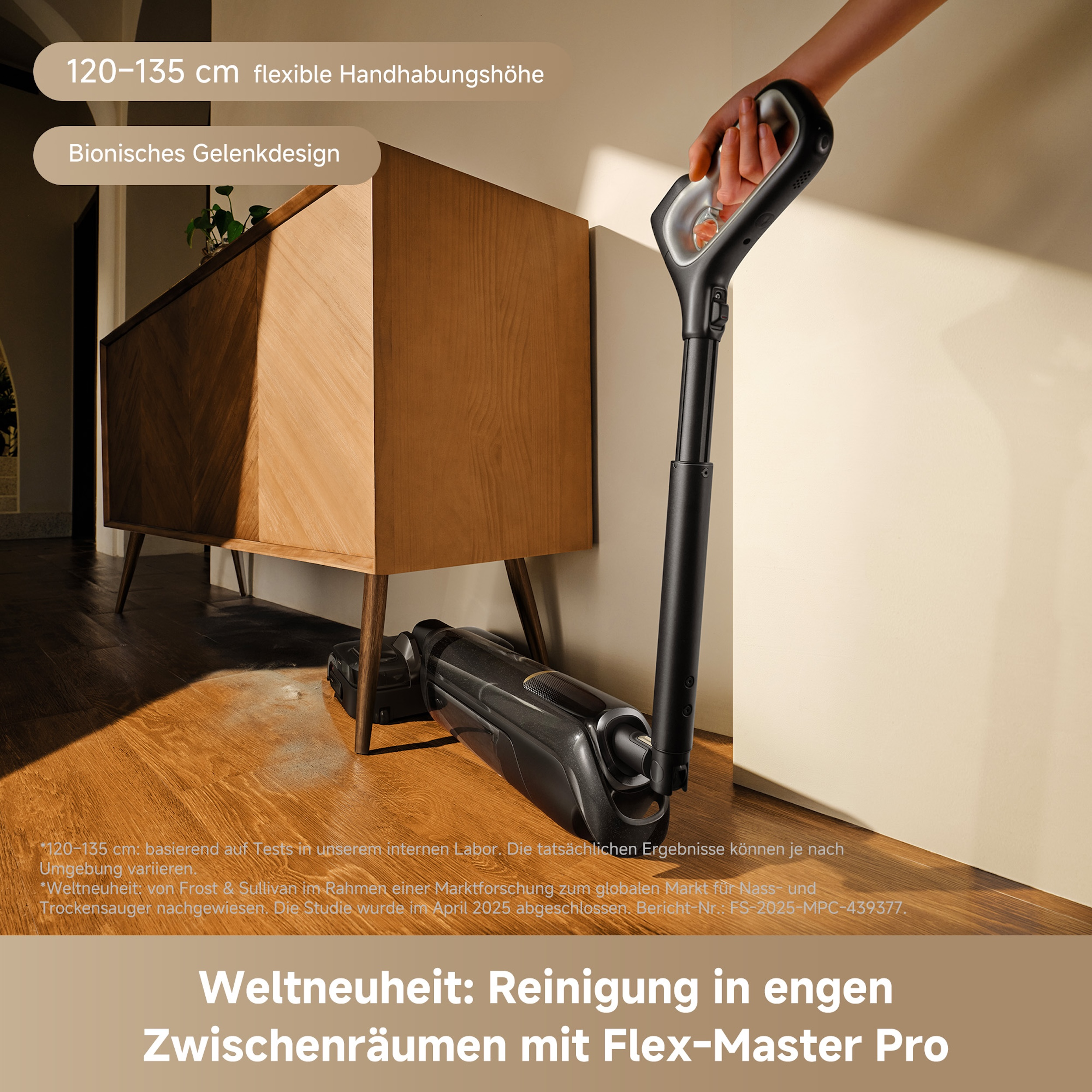 Eine Person hält einen schwarzen Staubsauger. Im Hintergrund sind ein Holzschrank und -boden zu sehen.