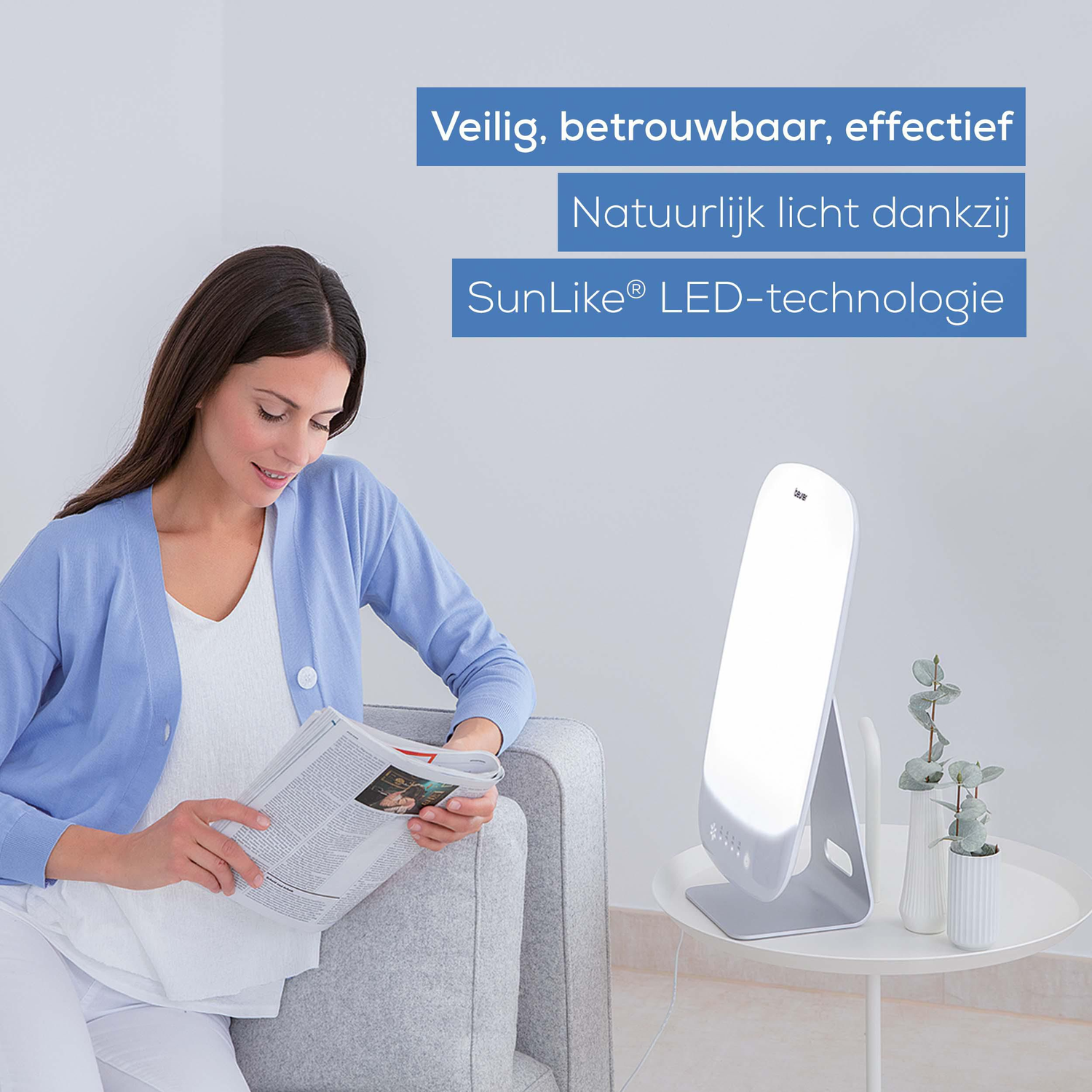 Vrouw leest een krant in de buurt van een lichttherapielamp. De tekst zegt: Veilig, betrouwbaar, effectief.