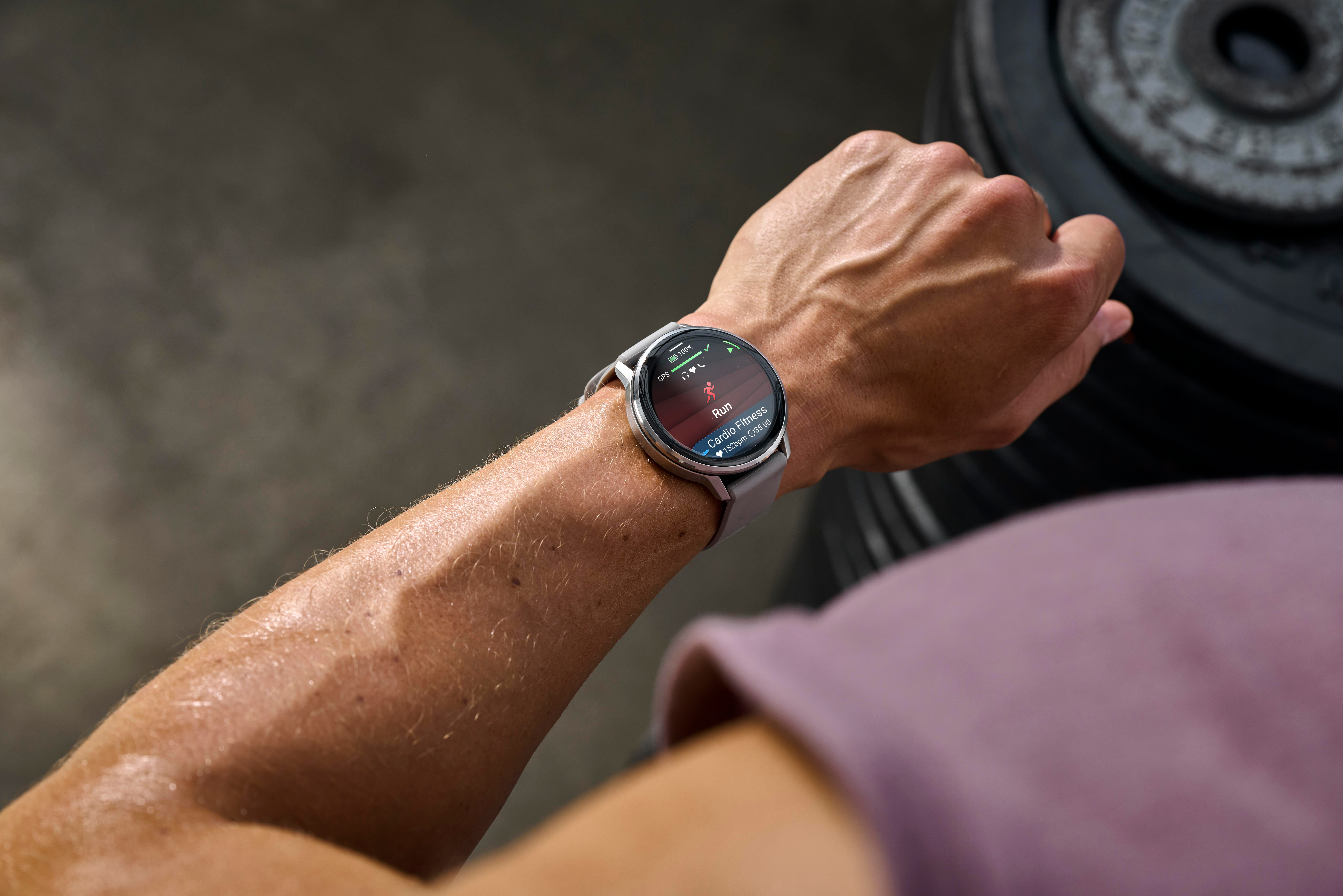 Eine Person, die während eines Trainings eine Smartwatch trägt. Die Uhr zeigt Laufdaten an. Der Arm der Person ist verschwitzt.