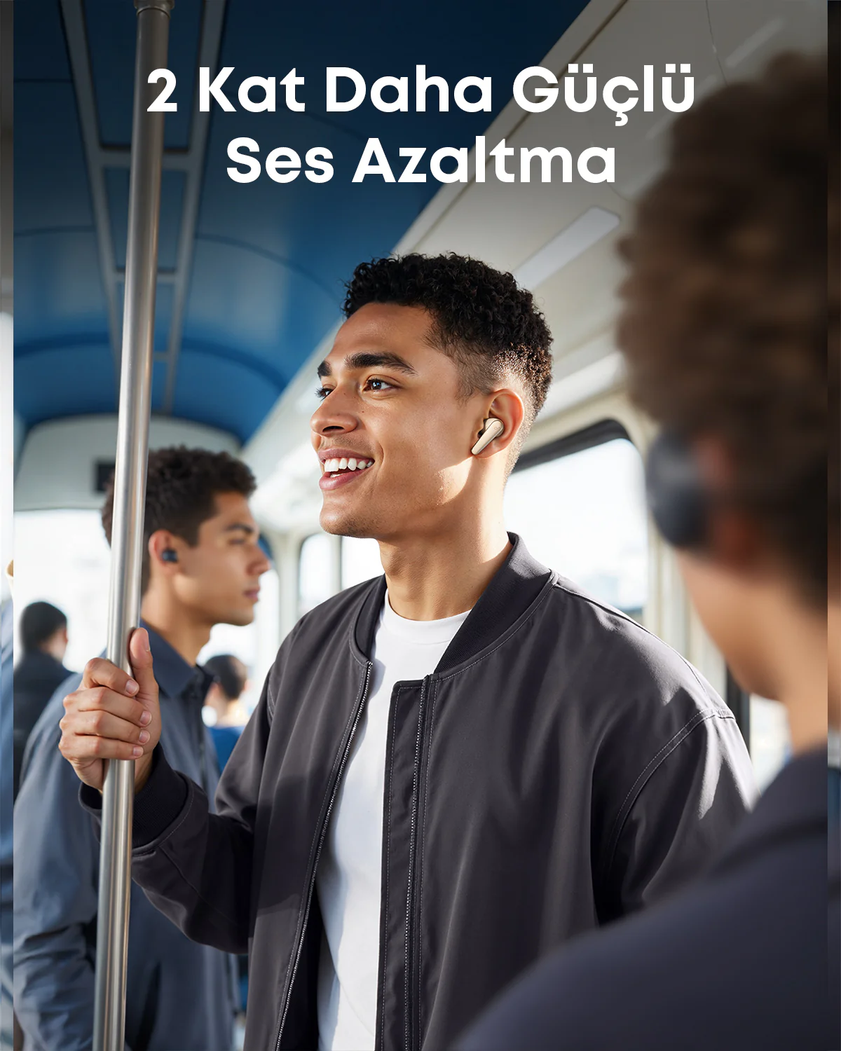 Trende ceketli, gülen bir adam. Kulaklık takıyor. Üstteki metin '2 kat daha güçlü gürültü engelleme' diyor.
