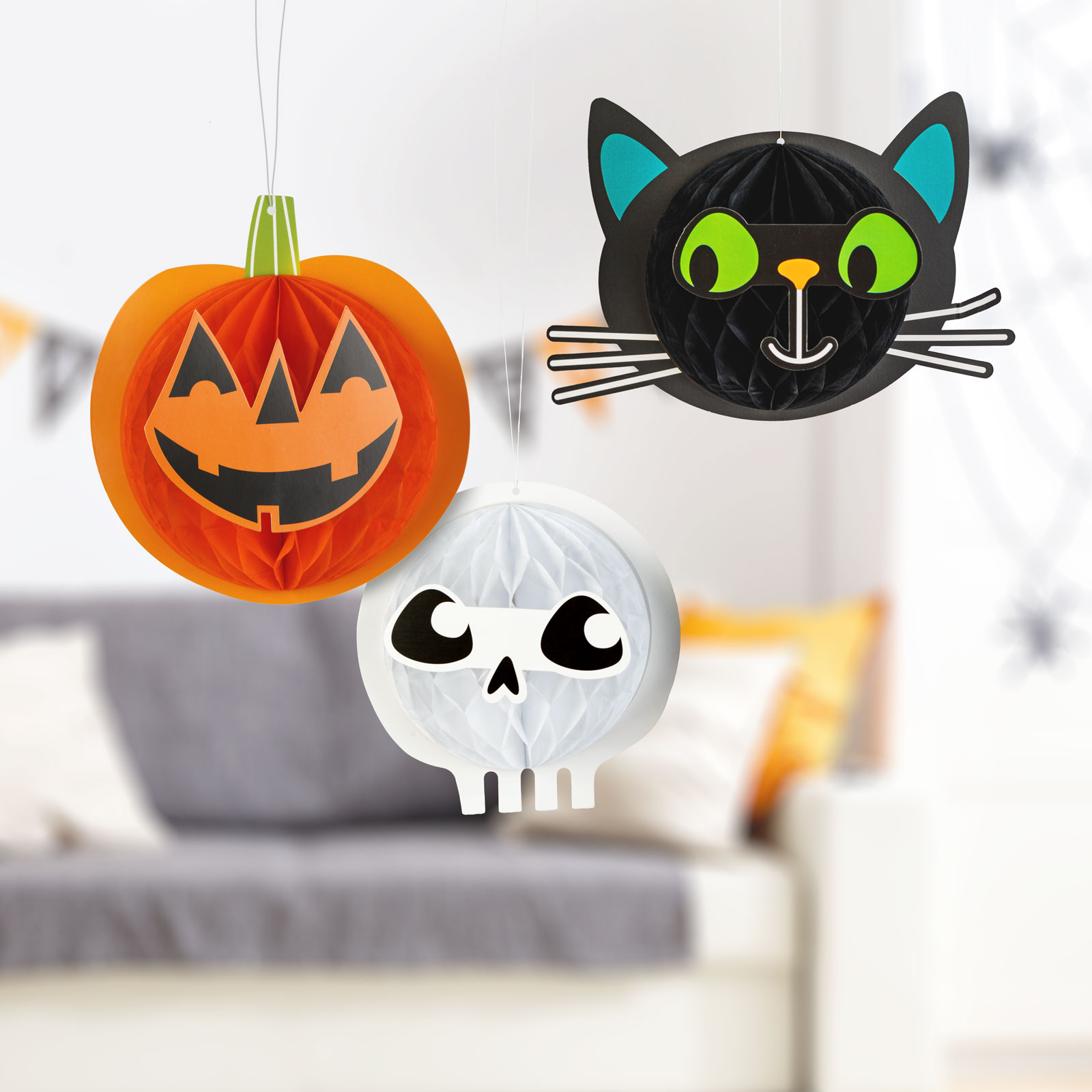 Halloween dekorációk: tök, macska és koponya lóg. Háttér: nappali kanapéval és dekorációkkal.
