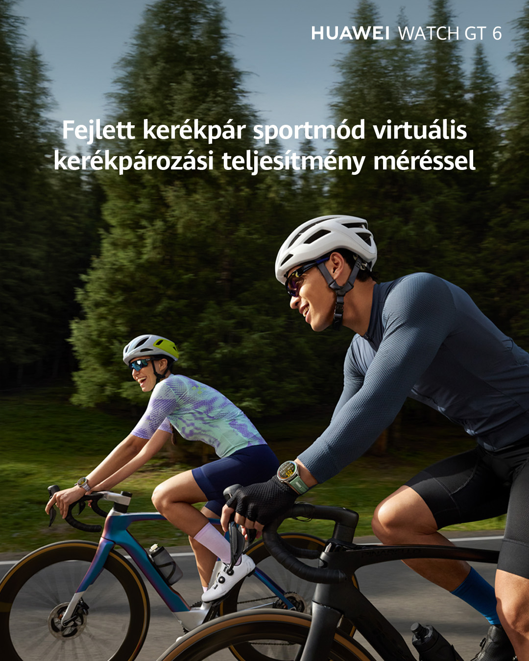 Két kerékpáros sisakban biciklizik. Egy okosóra van az egyik csuklón. A háttérben fák láthatók.