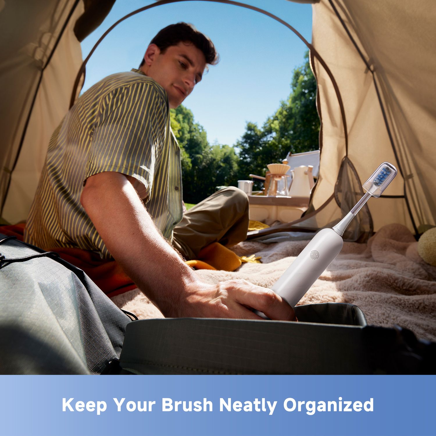 Man in tent with toothbrush. He's holding the toothbrush. Tent interior with blurred background, includes trees and sky.