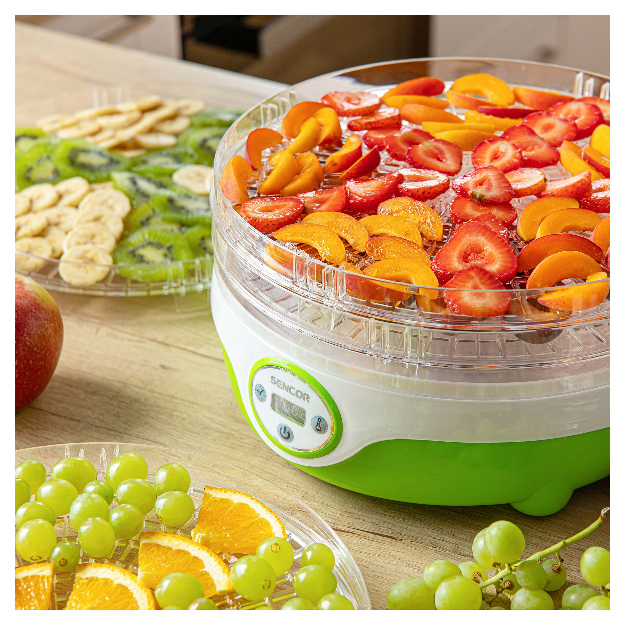 Suszarka do żywności z truskawkami, morelami, winogronami, kiwi, bananami i plastrami pomarańczy.