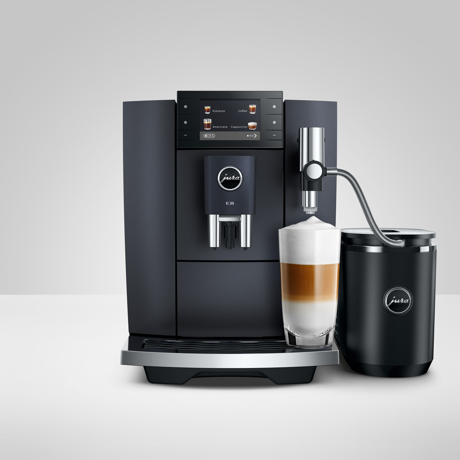 A black Jura coffee machine with a glass of latte macchiato. Buttons for espresso, cappuccino, and americano are visible.