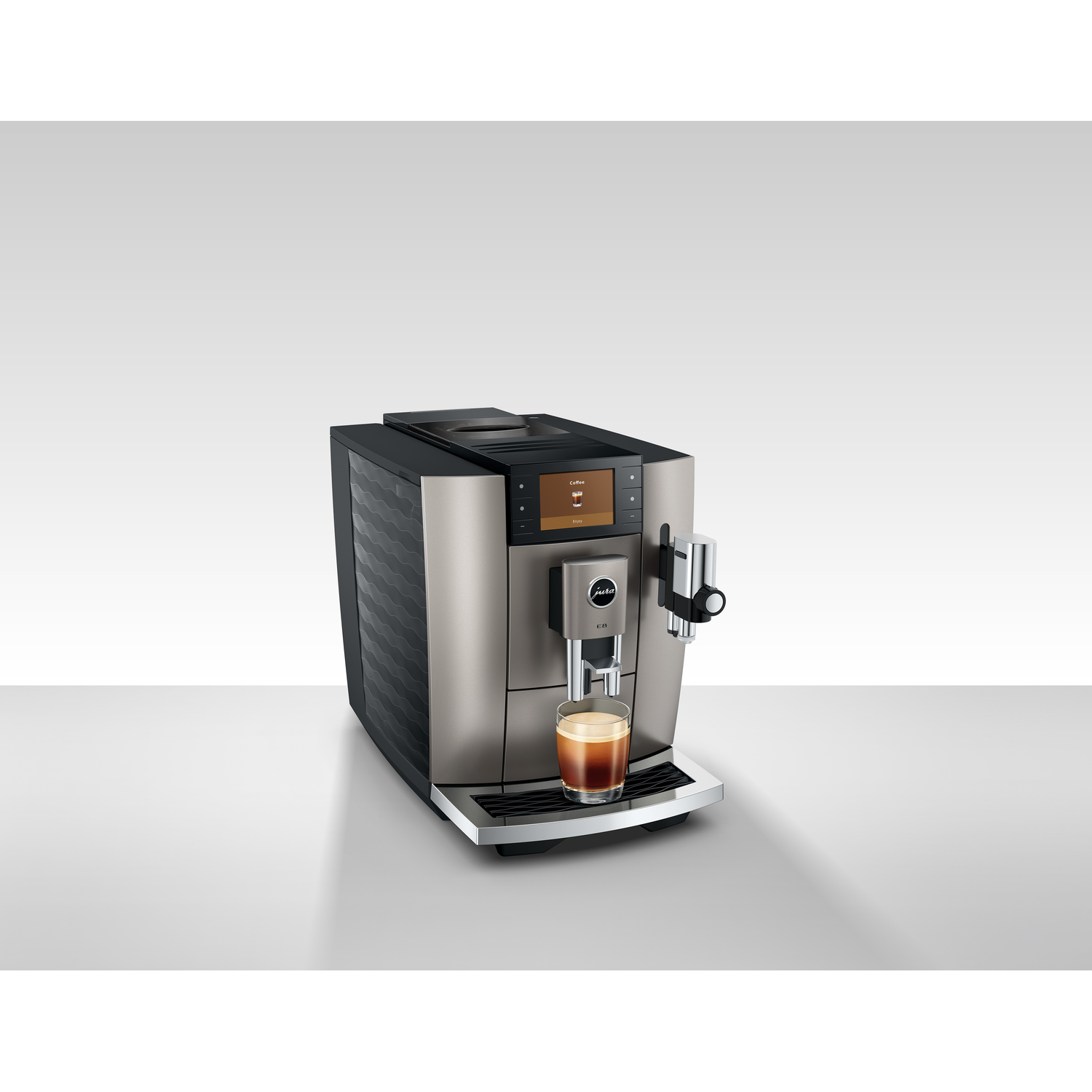 A silver and black Jura E8 coffee machine with a glass of coffee in front of it. A touch screen is visible.