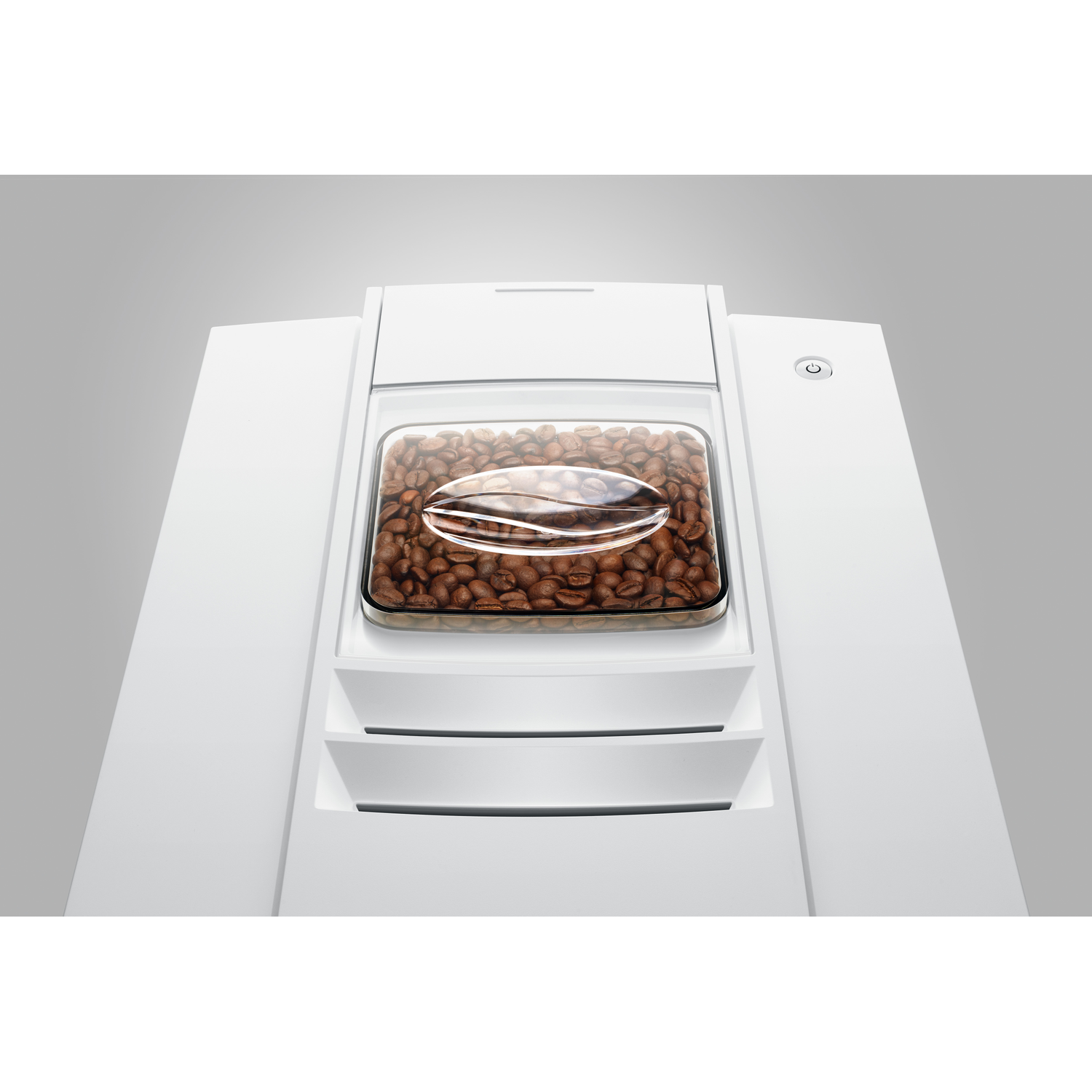 A white coffee machine with a container of coffee beans. The machine has a power button, and two drawers.