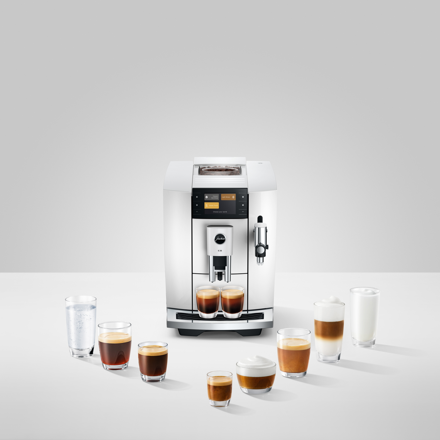 A white Jura coffee machine with various coffee drinks around it, including espresso, latte, and cappuccino, on a white surface.