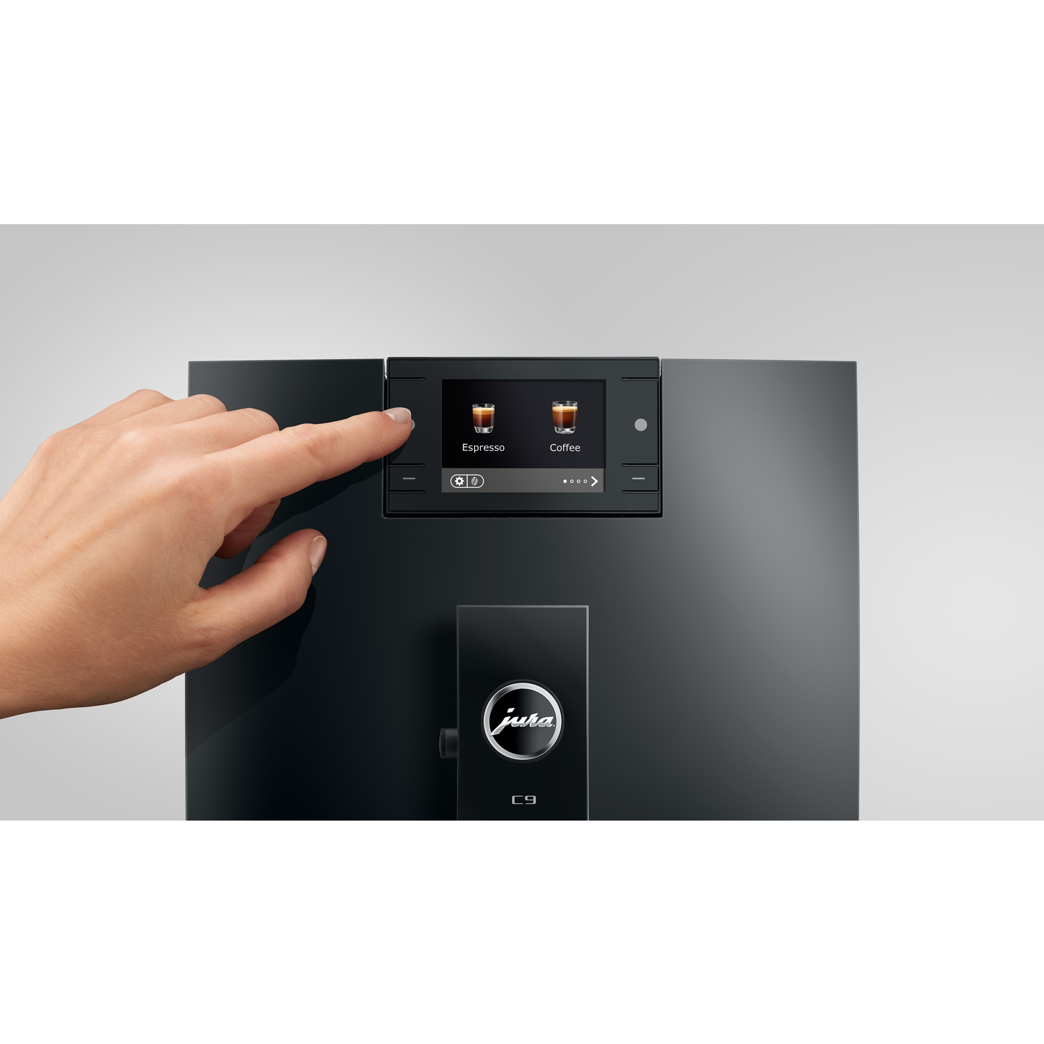 A hand touching an espresso machine screen. The screen displays options, with an espresso selection highlighted. The machine is black.