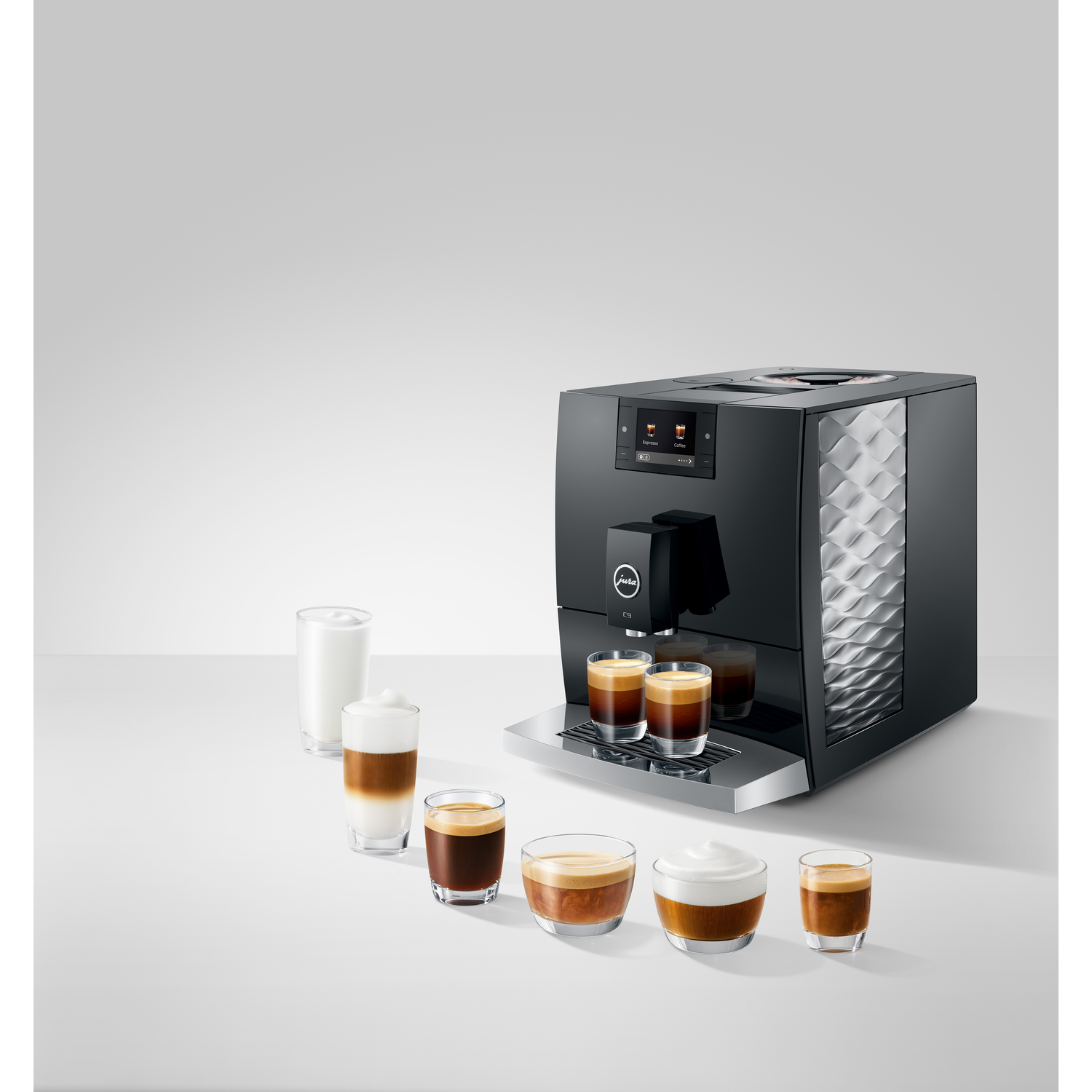 A black coffee machine with several coffee drinks in glasses. A glass of milk is on the left.