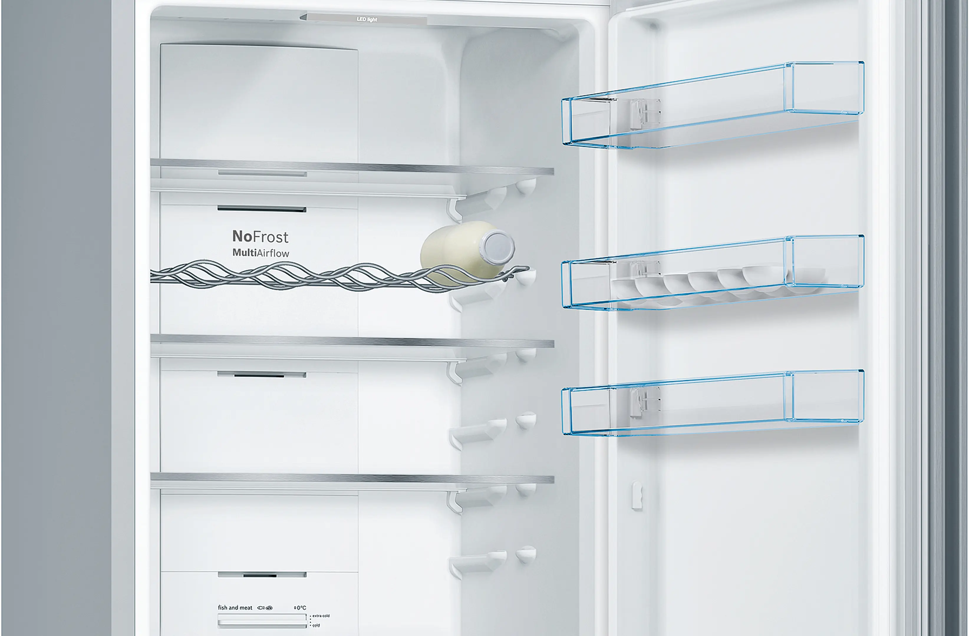 Un refrigerador abierto. Estantes y bandejas plásticas transparentes. Botella en rejilla metálica. Con 'No Frost'.