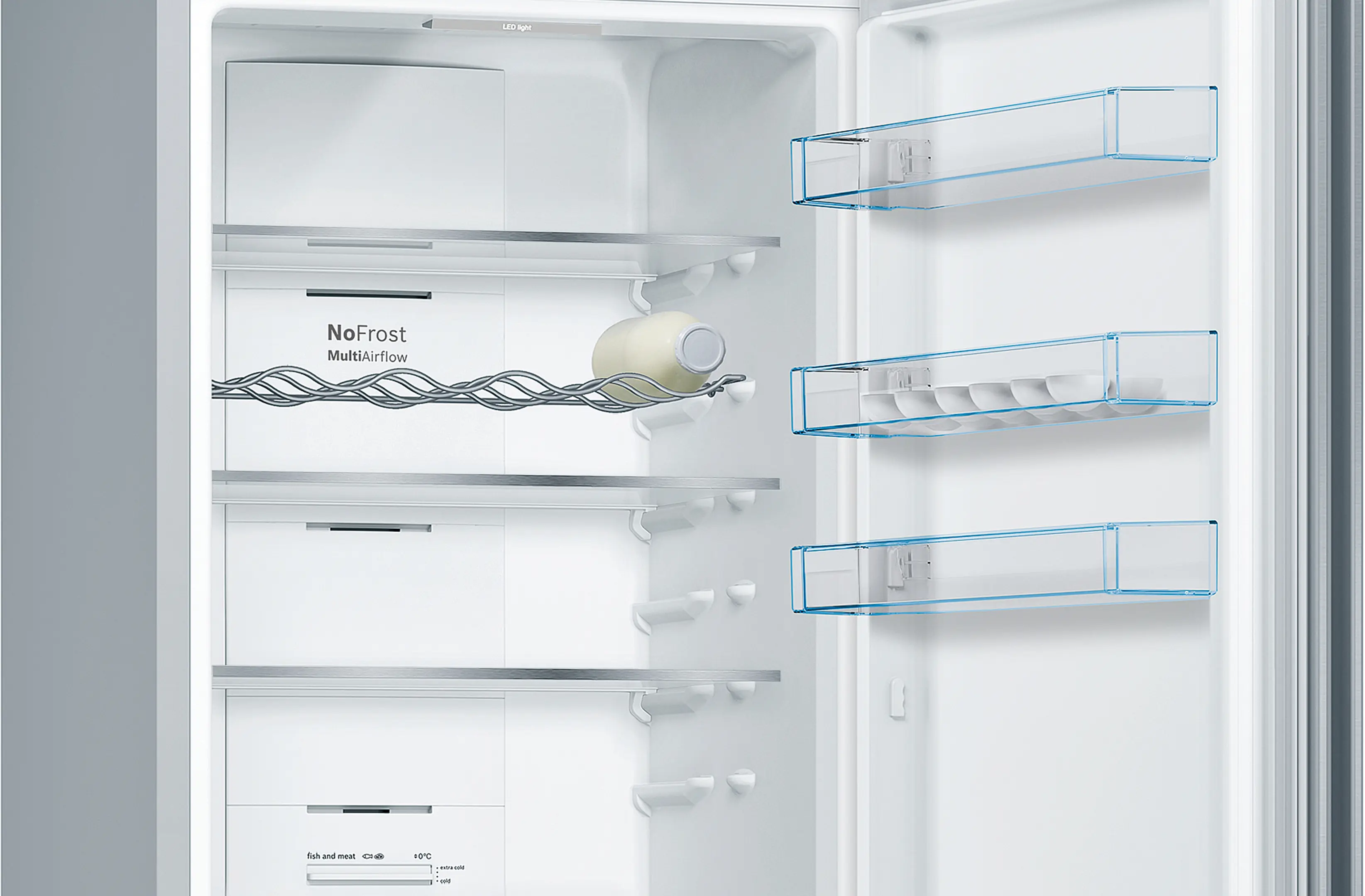 Interior de refrigerador blanco abierto. Estantes, botella de leche y cajones visibles. Ribete azul.