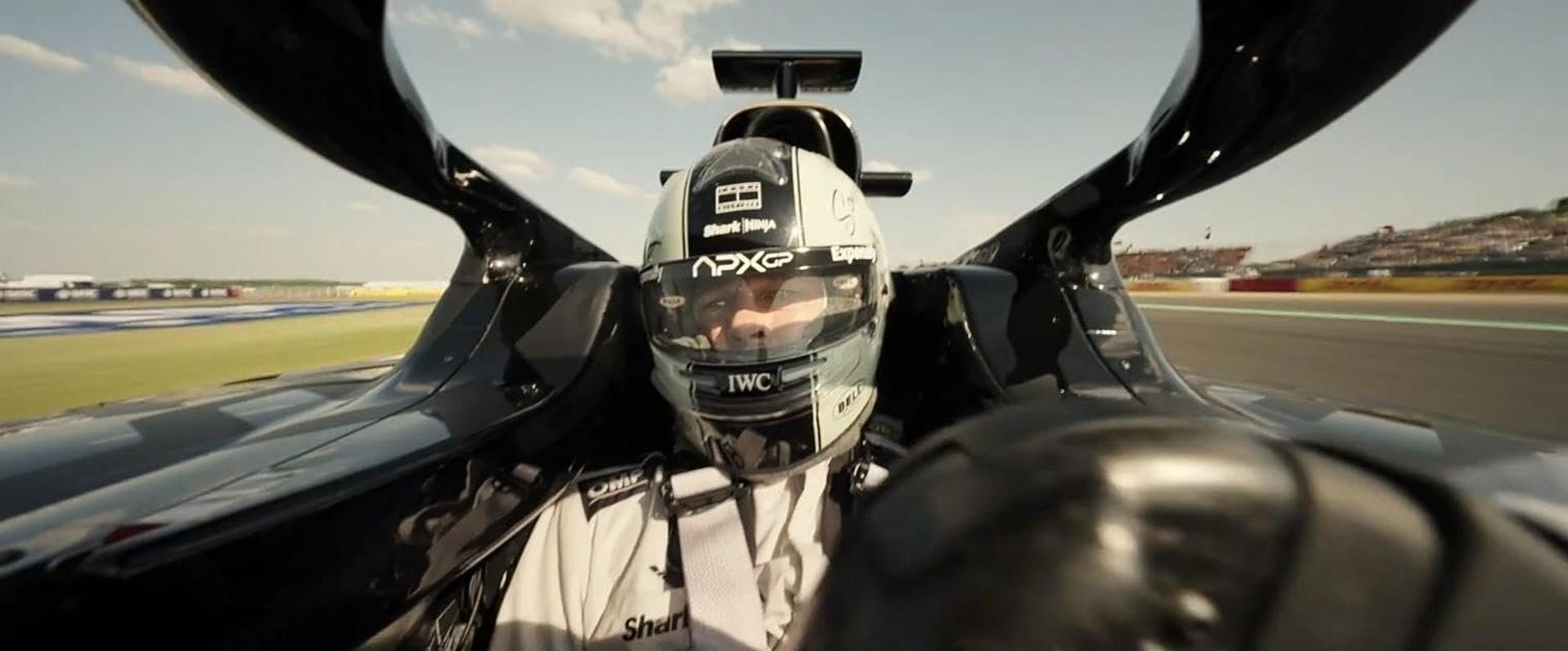 Ein Fahrer in einem Rennwagen, mit Helm, konzentriert sich auf die Strecke. Das Auto ist schwarz und elegant.
