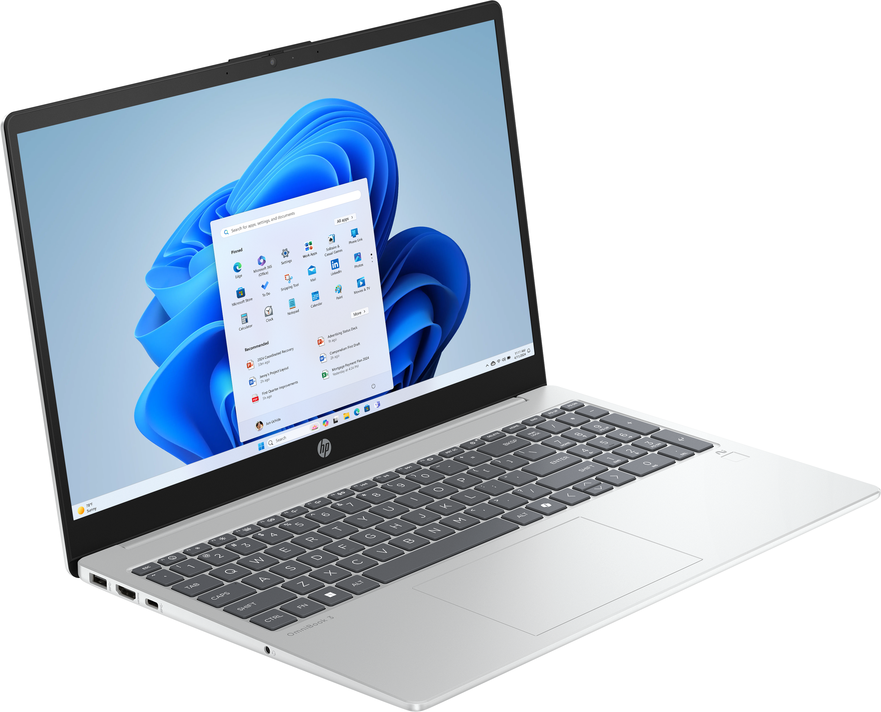 Silberner Laptop offen, Windows 11-Oberfläche. Tastatur sichtbar, Bildschirm zeigt Apps.