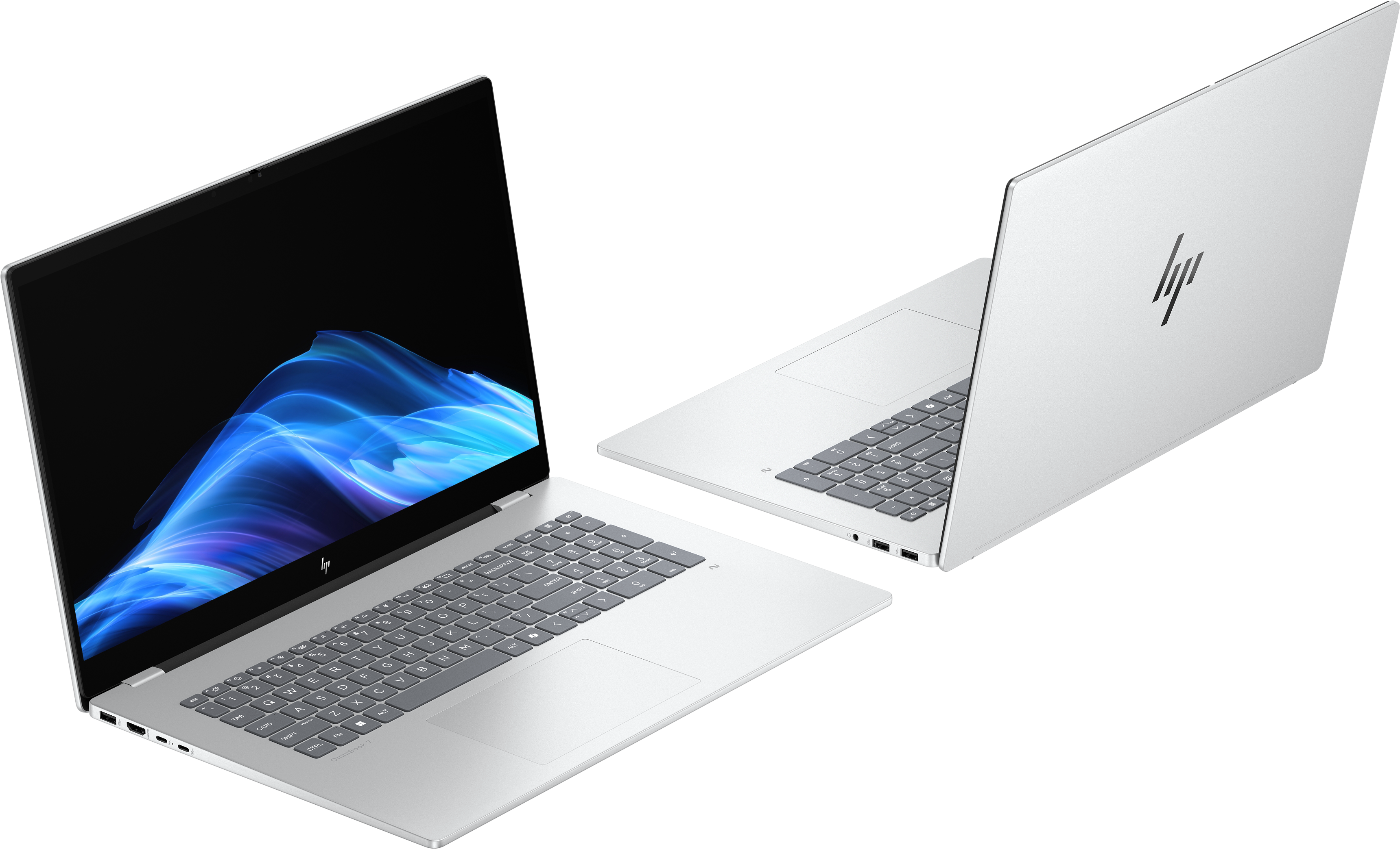 Due laptop HP argentati. Uno è aperto, mostra un design blu e bianco sullo schermo. Sfondo nero.
